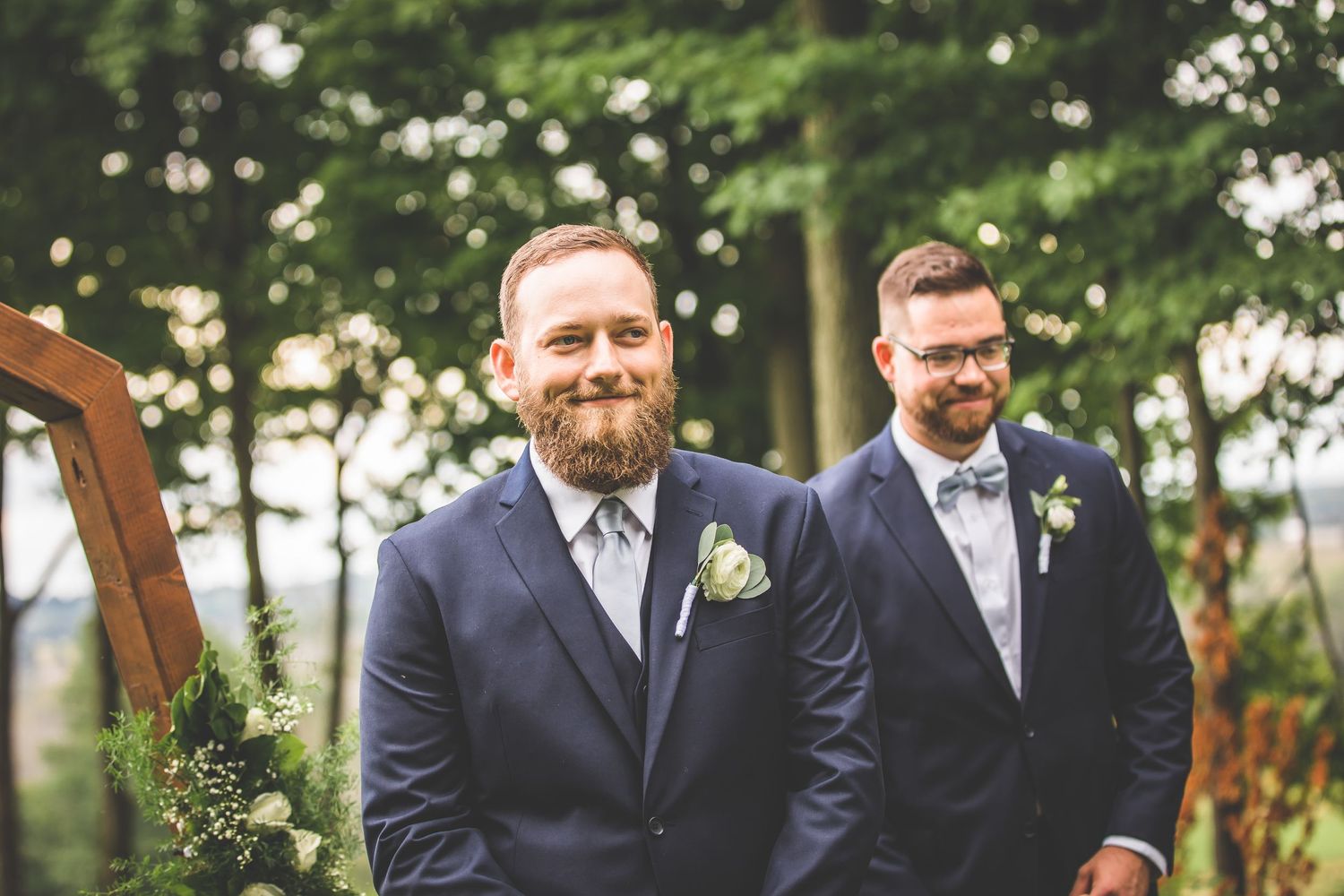 Groomsmen in navy suits standing together at outdoor wedding.