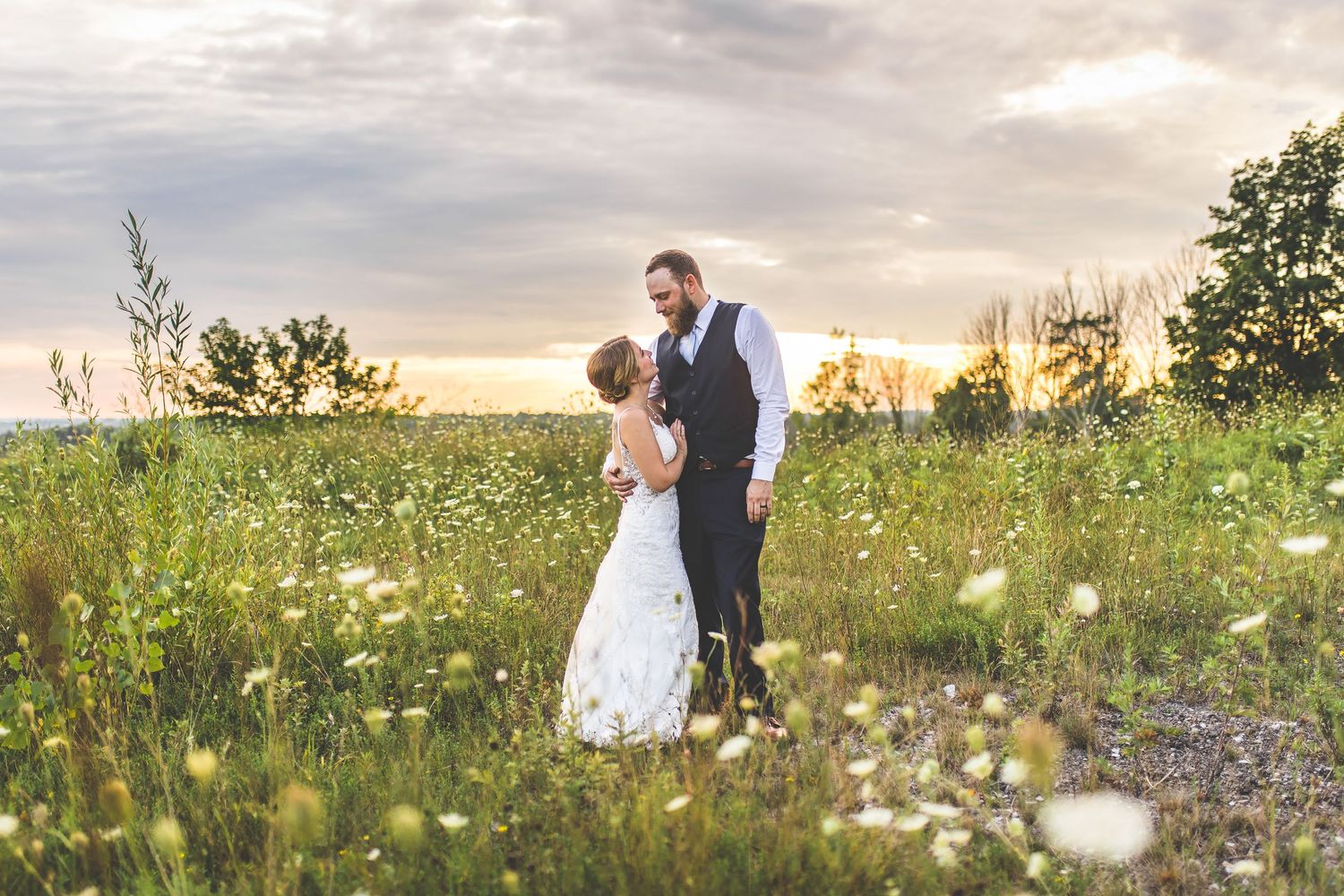 A couple shares a romantic moment in a wildflower meadow at sunset.