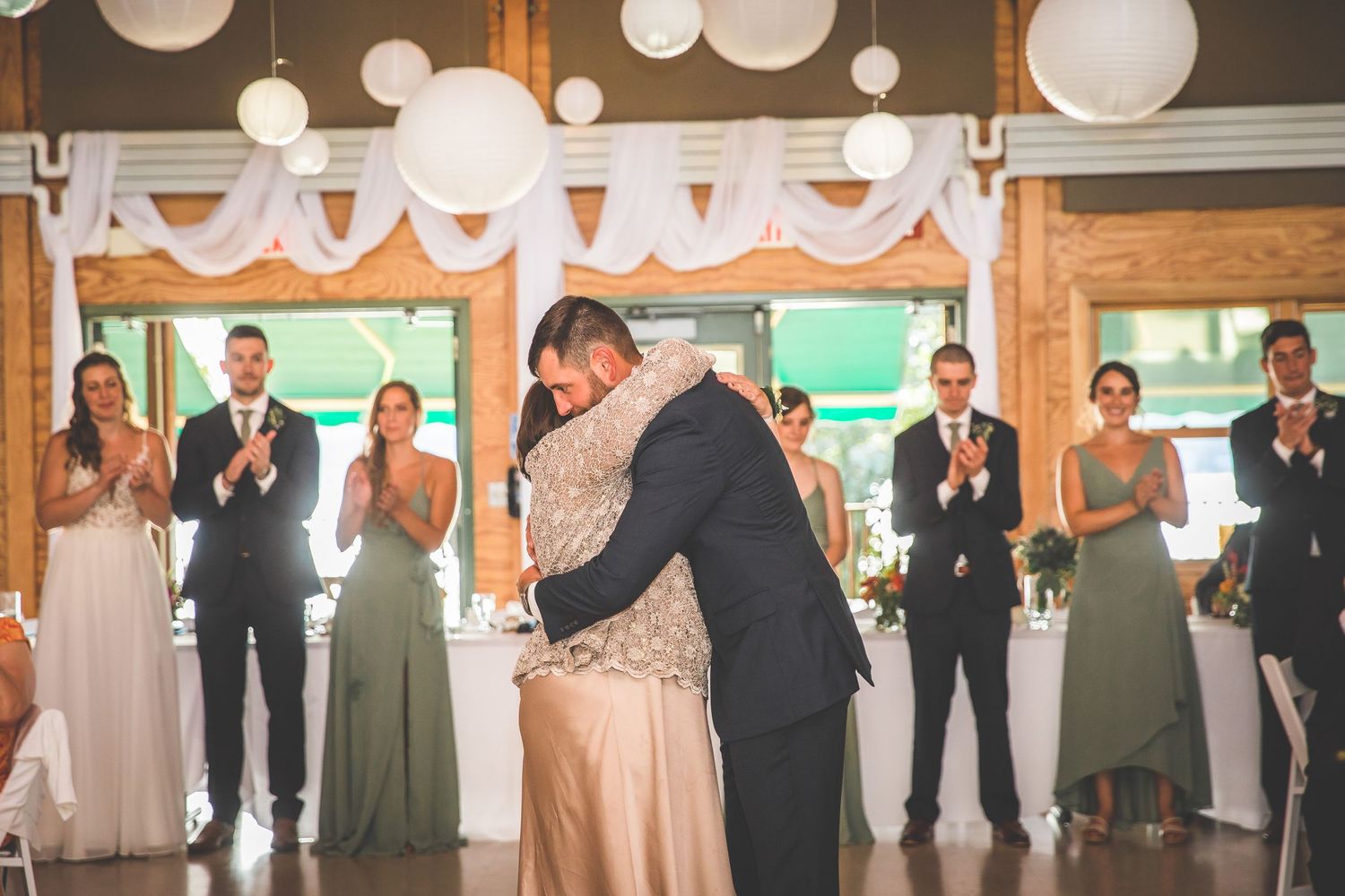 Wedding celebration in a barn-style venue with white lantern decorations and wooden walls.