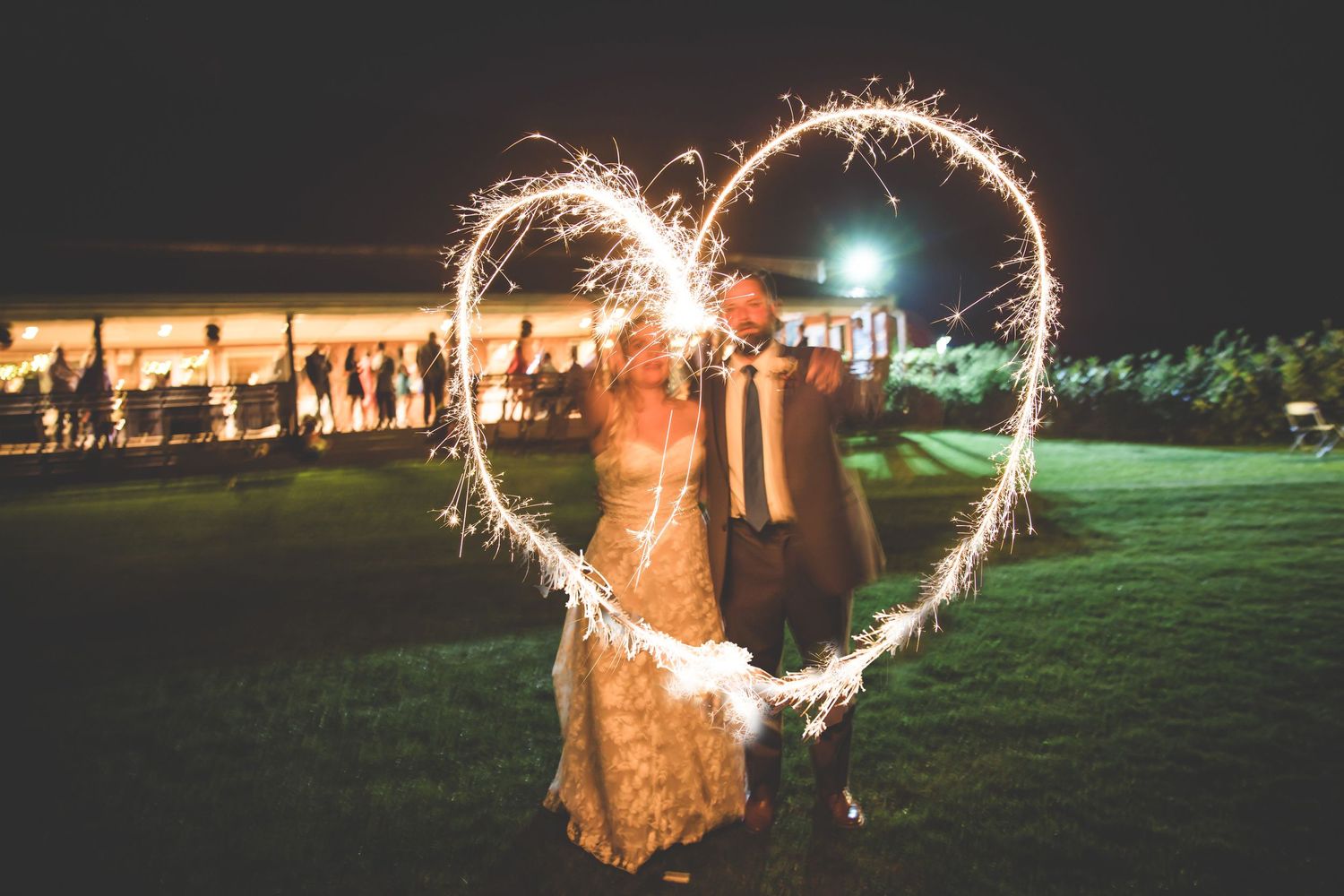 Wedding sparkler exit creates magical light trails against the dark night sky.