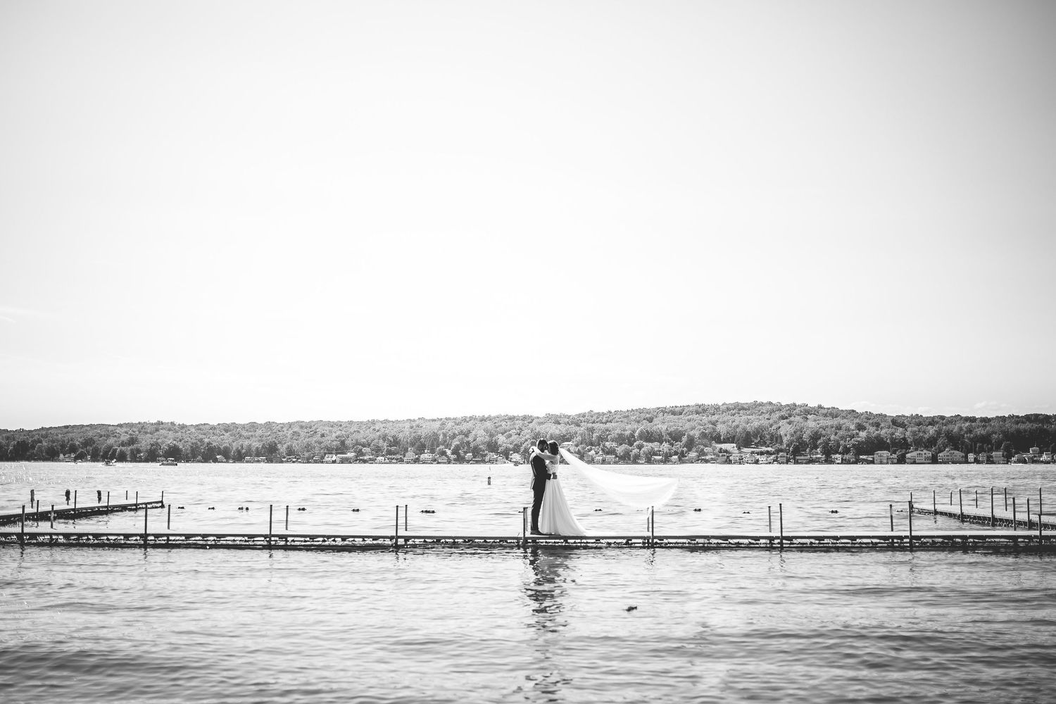 Scenic black and white waterfront landscape with dock extending into calm waters.