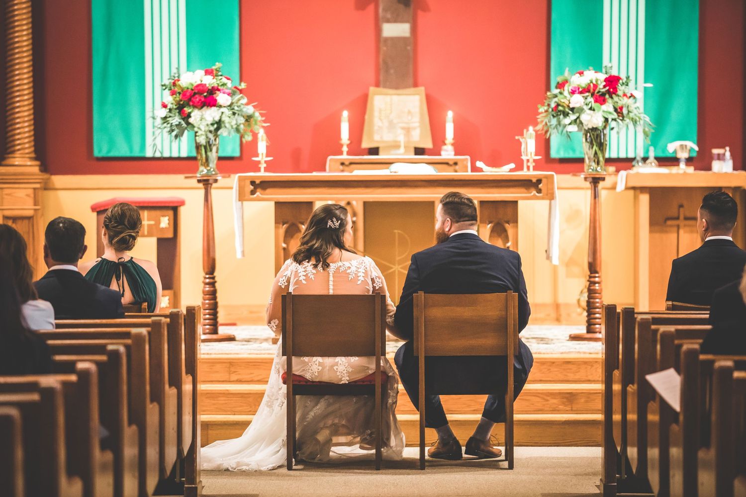 Wedding ceremony in church with red and green decor elements.