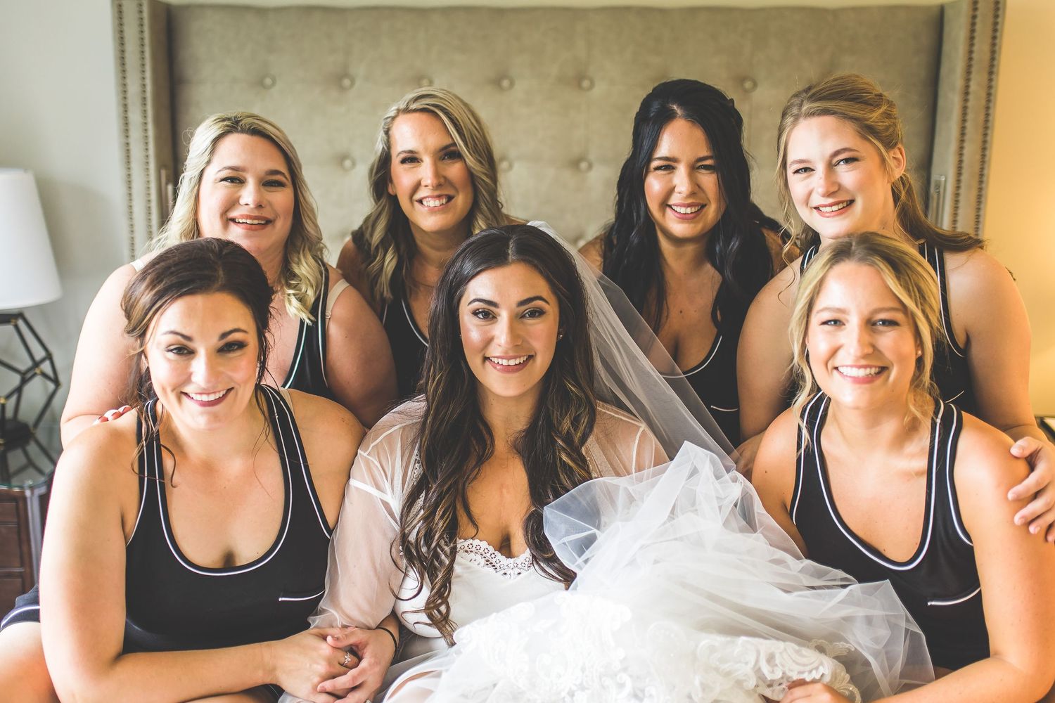 Bridesmaids in matching black dresses share joyful moments during wedding preparations.