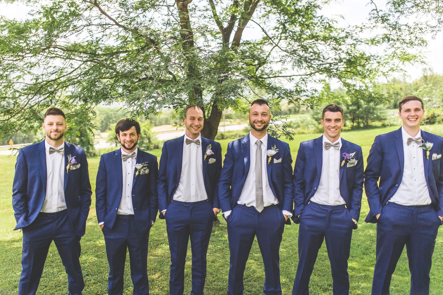 Groomsmen line up wearing matching navy suits and ties for formal wedding photos.