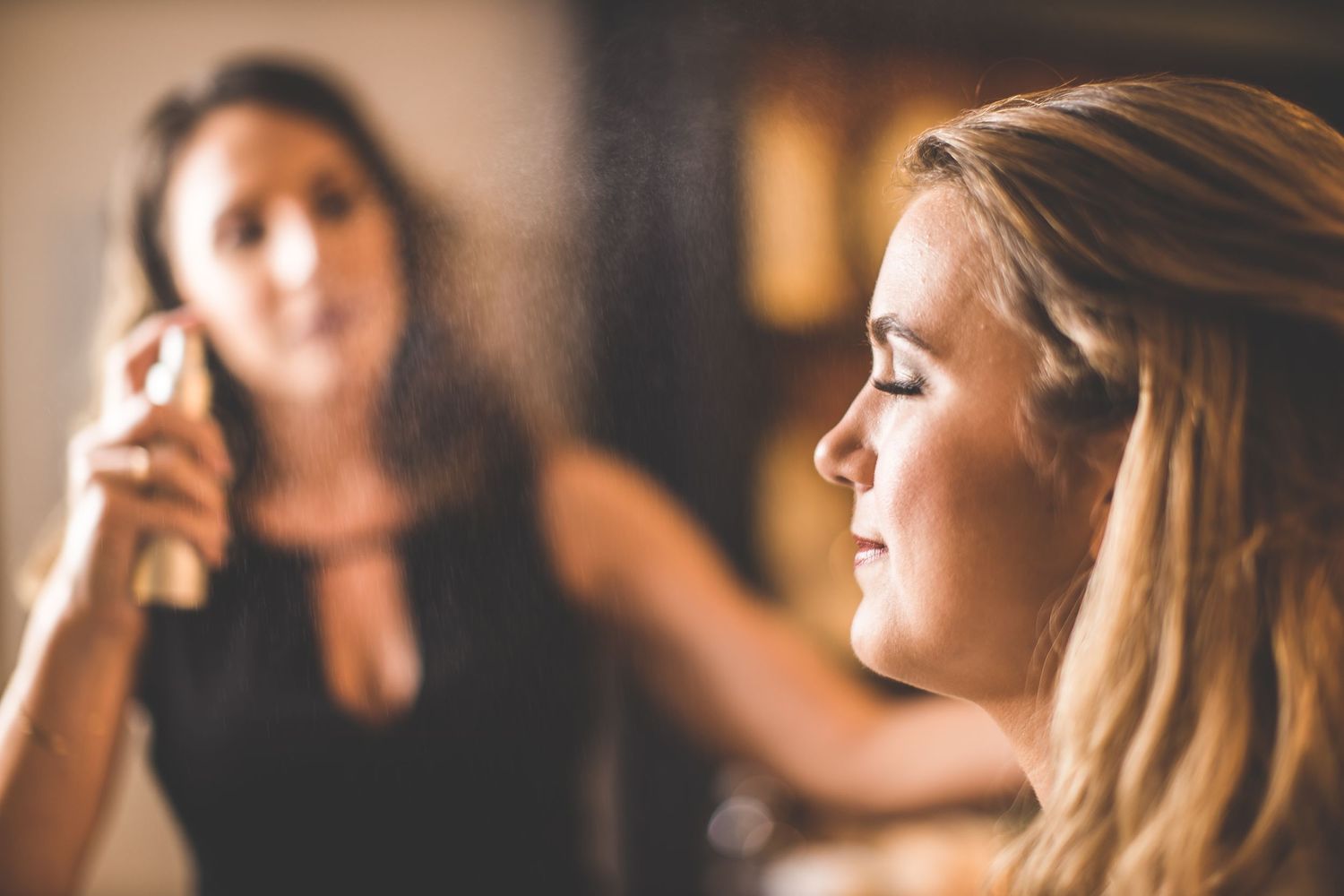 Getting ready scene with soft focus makeup application in warm lighting.