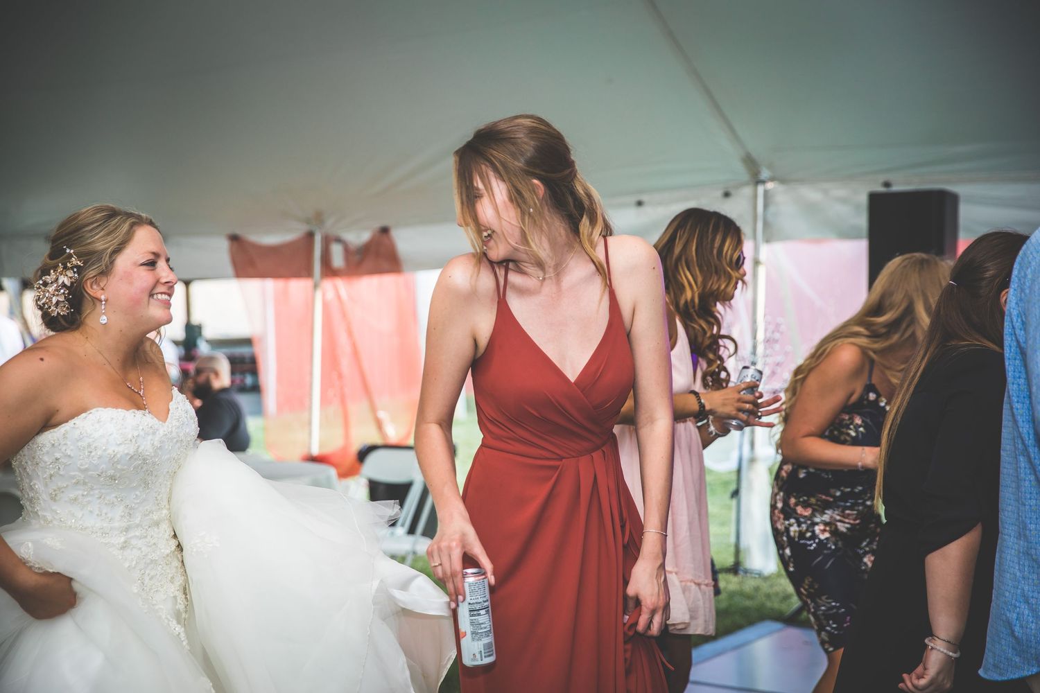 Wedding celebration under a tent with guests in colorful attire dancing.