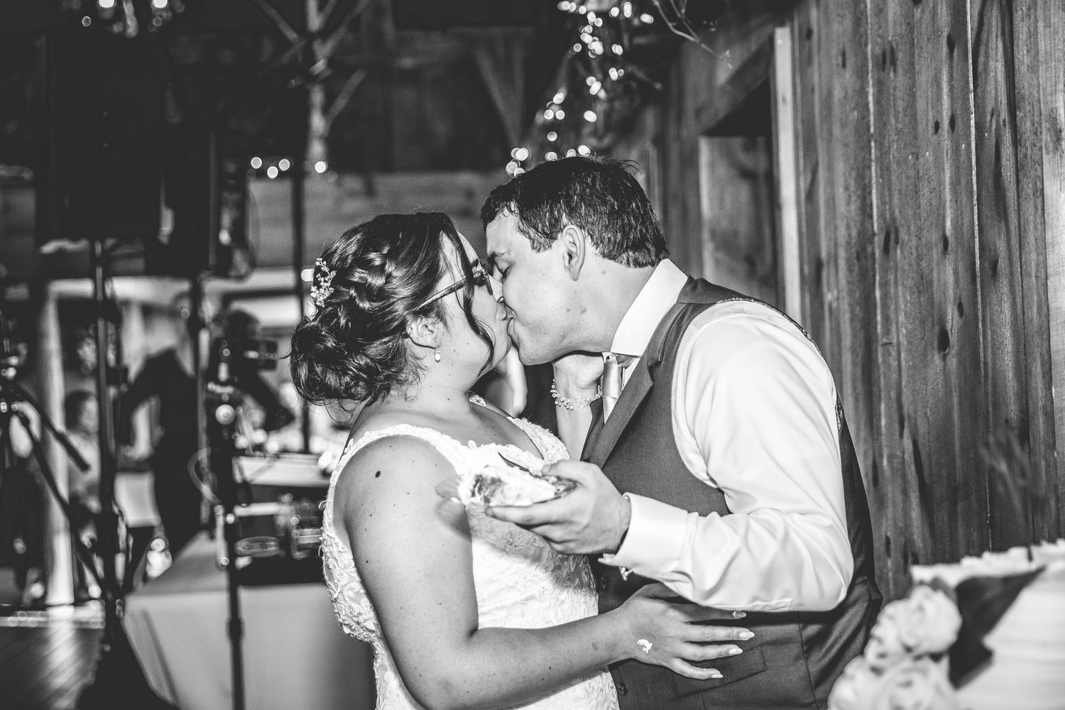 Playful cake cutting moment between newlyweds at rustic barn wedding venue.