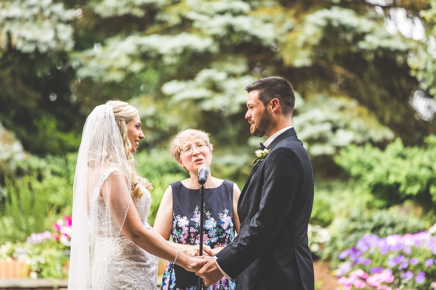 Intimate outdoor wedding ceremony with couple exchanging vows surrounded by lush greenery.