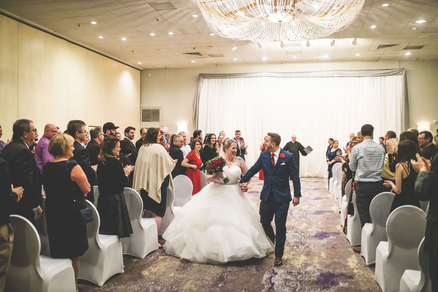 Wide angle view of wedding reception with guests dancing and celebrating on the dance floor.