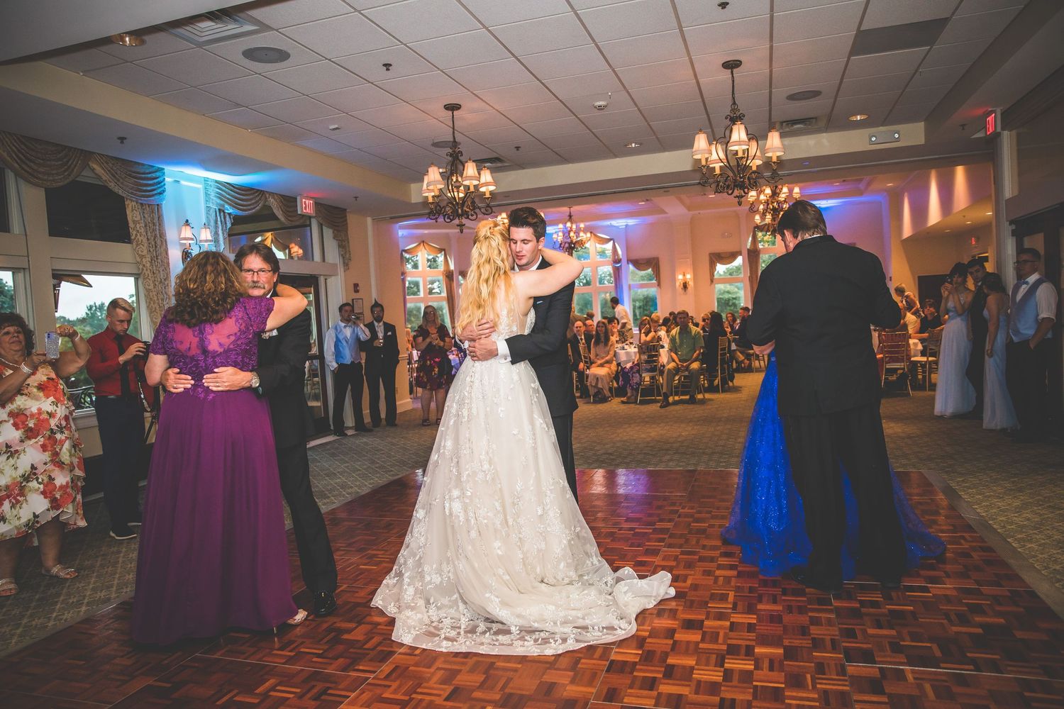 Wedding celebration in a grand ballroom with chandelier lighting and checkered dance floor.