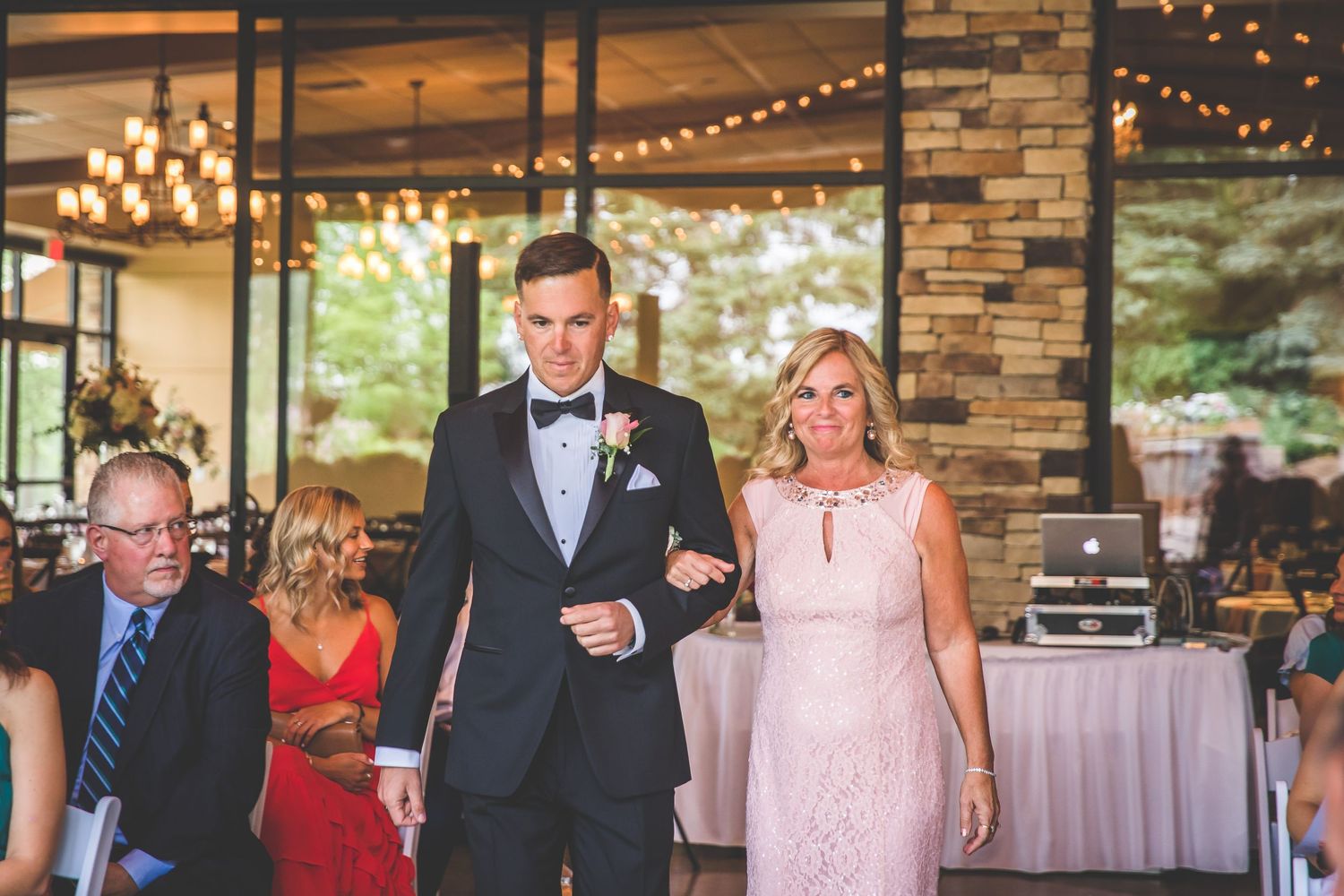 Modern reception hall with string lights and stone accents during a wedding celebration.