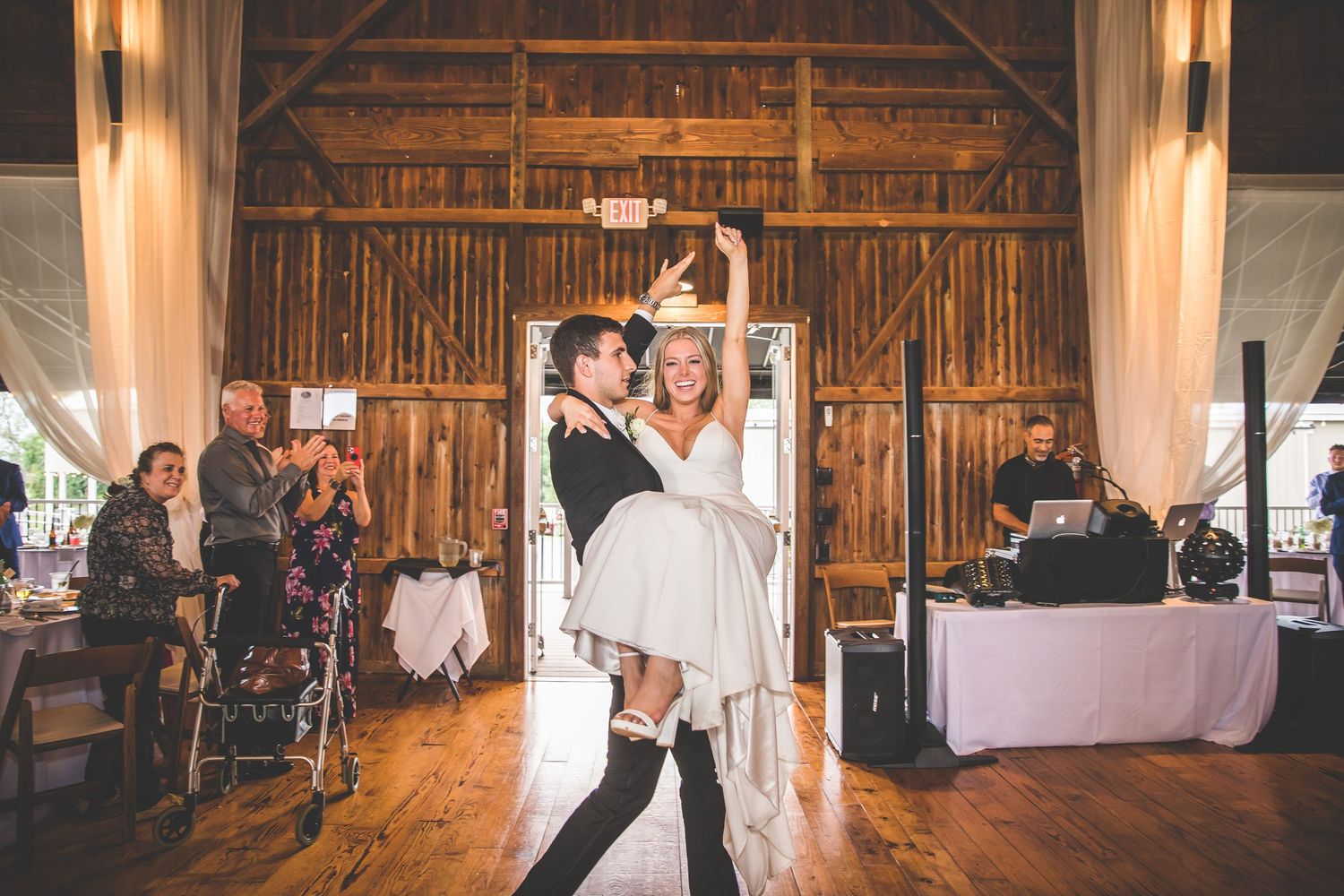 Dancing celebration in rustic barn venue with wooden beams and ambient lighting.