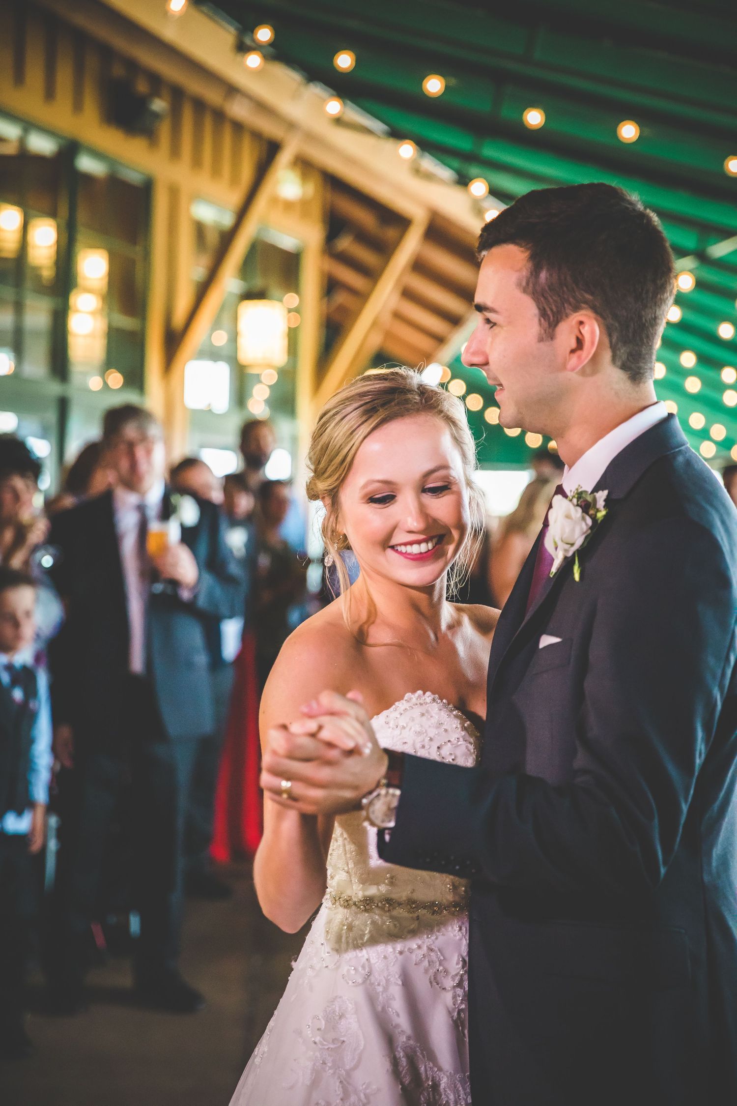 Couples dance together under twinkling lights at an evening wedding reception.