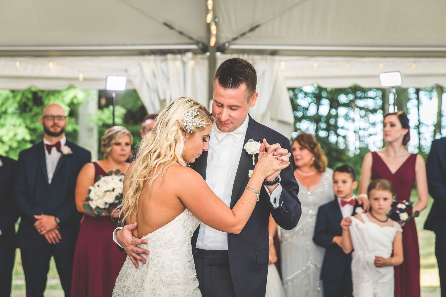 Wedding ceremony and celebration moments under a white tent outdoors.