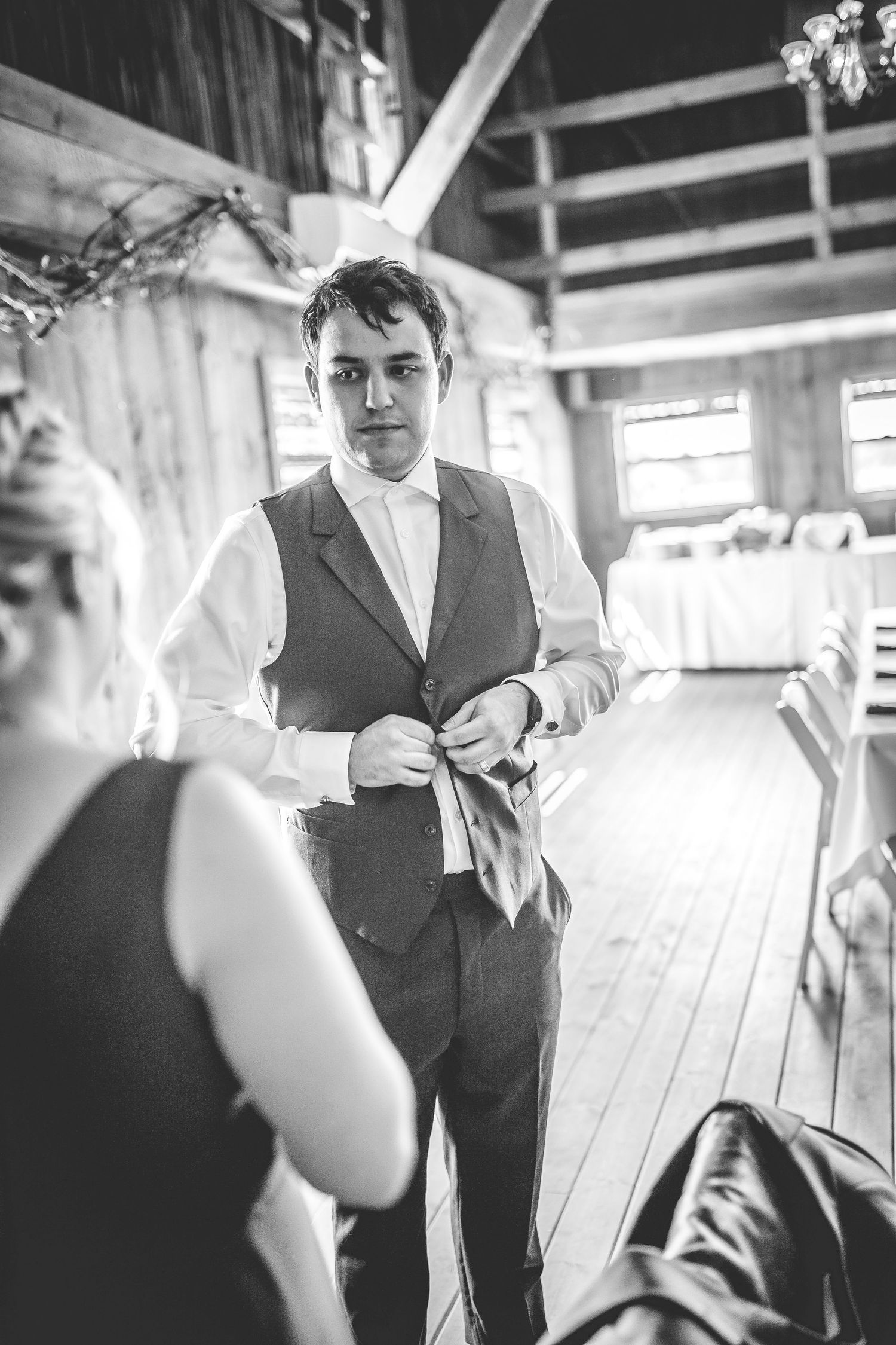 Black and white photos of wedding preparations inside a rustic wooden barn setting.