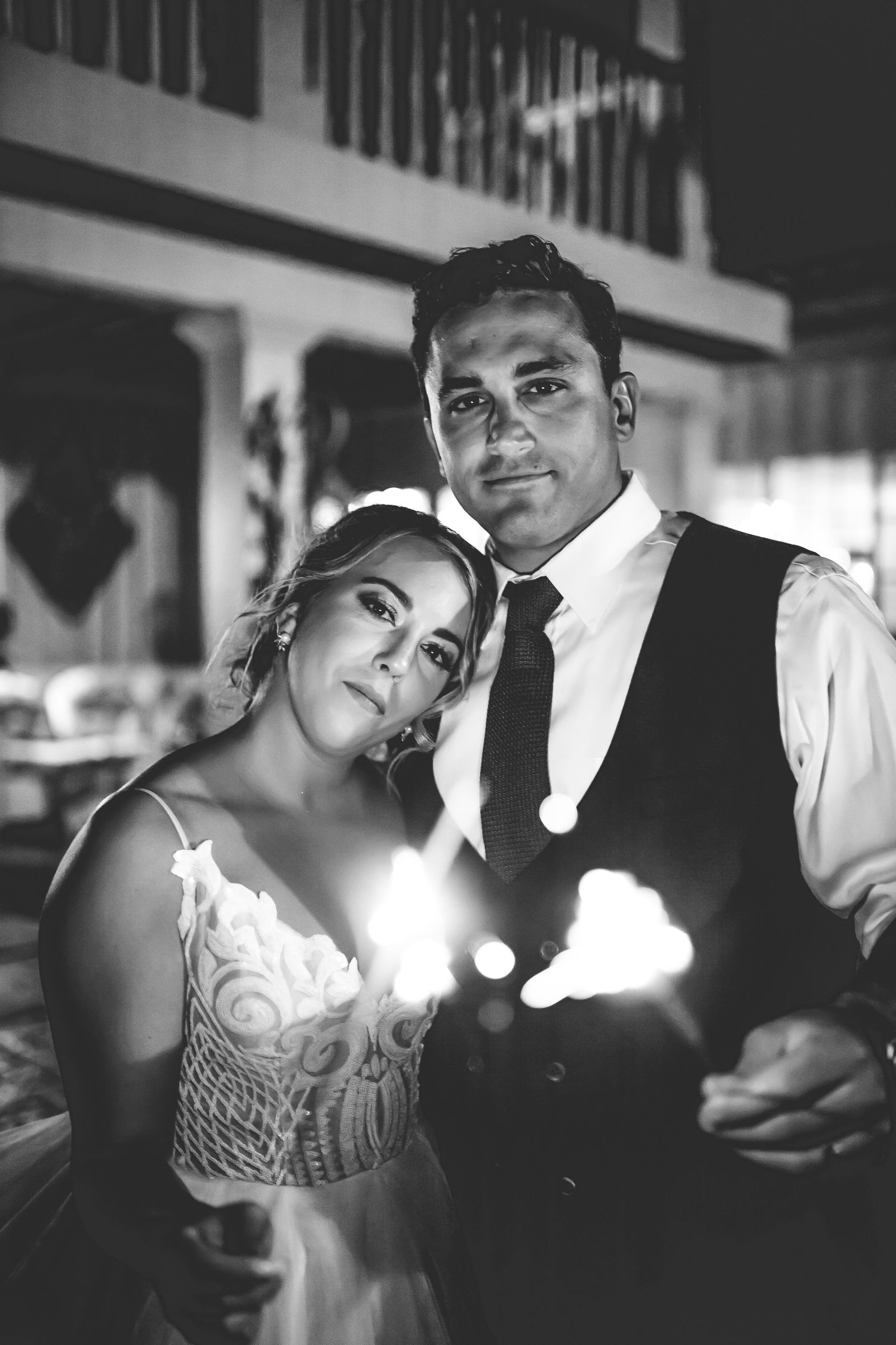 A romantic black and white portrait of a couple holding sparklers at their wedding reception.