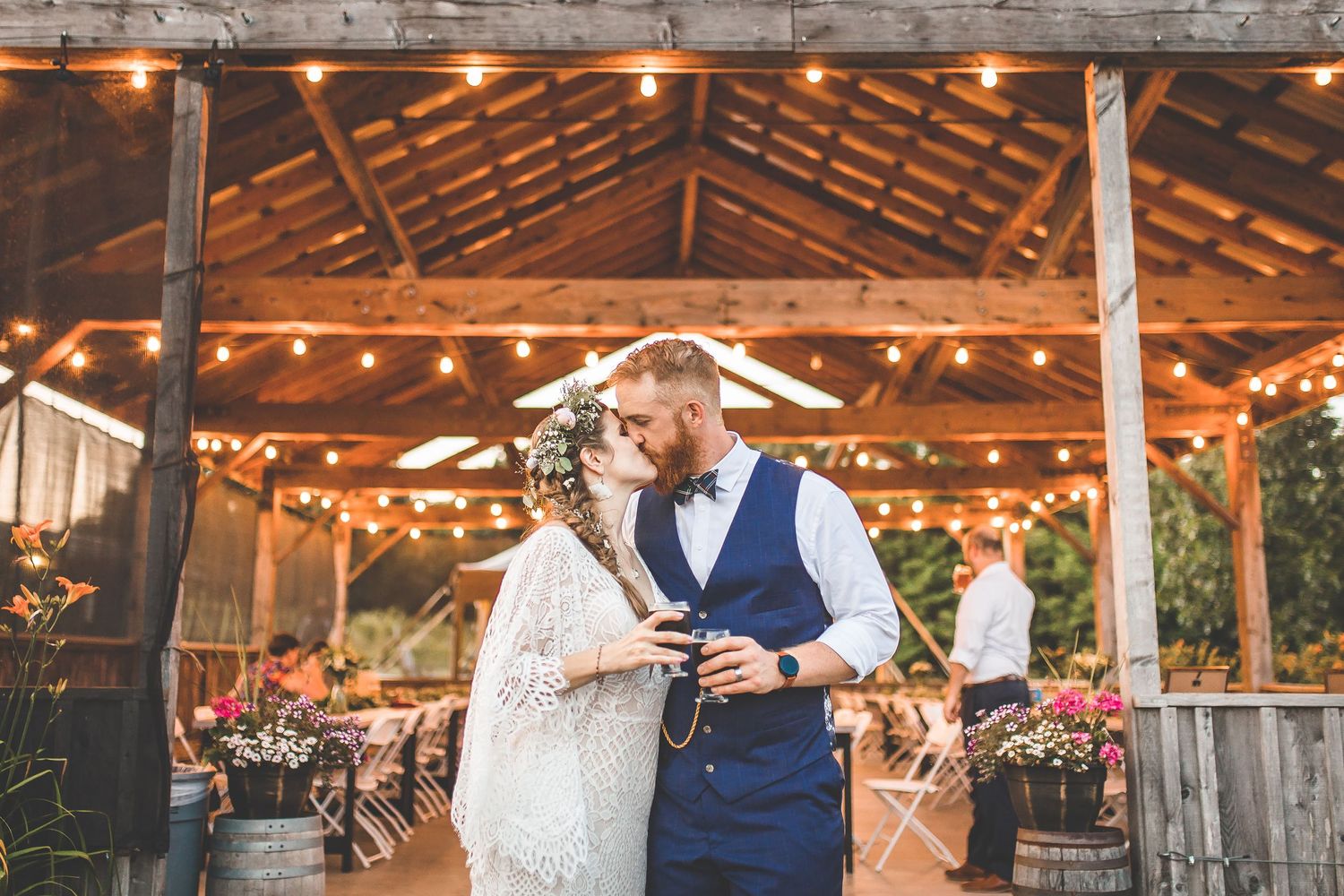 Rustic outdoor wedding venue with wooden beams and string lights creating a romantic atmosphere.