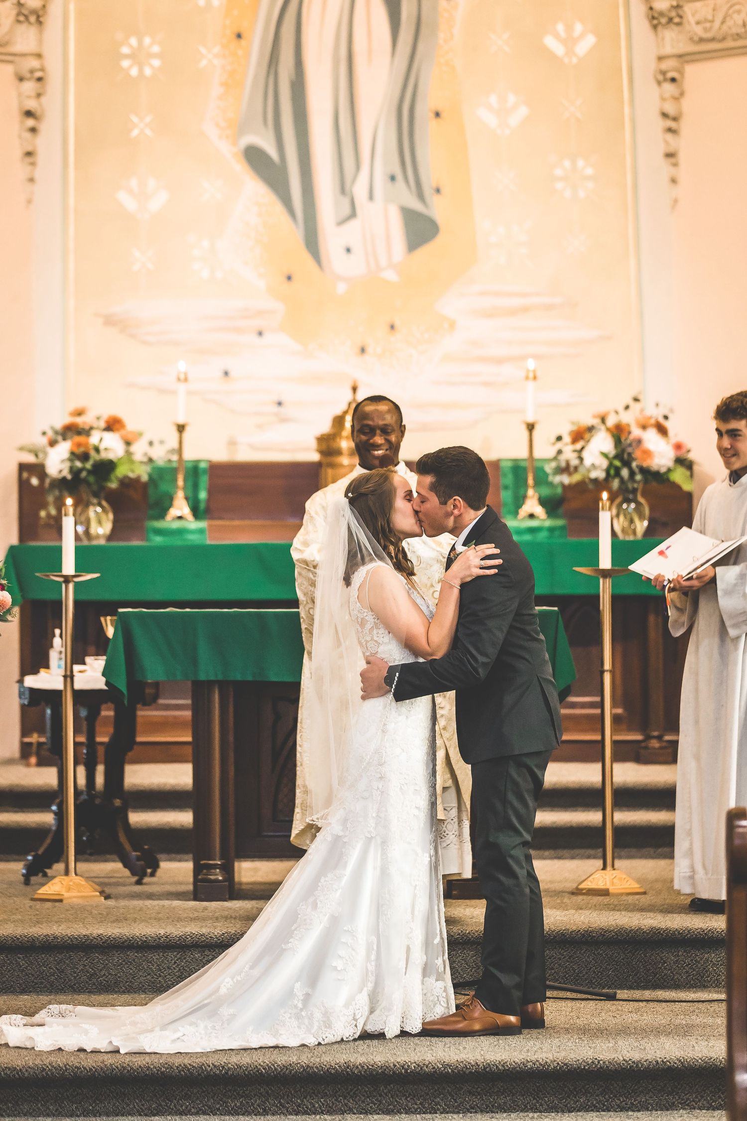 Wedding couple shares intimate moments in a church with green altar decorations.
