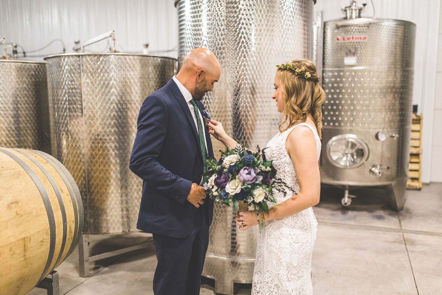 A romantic first look moment captured between wine tanks at a winery wedding.