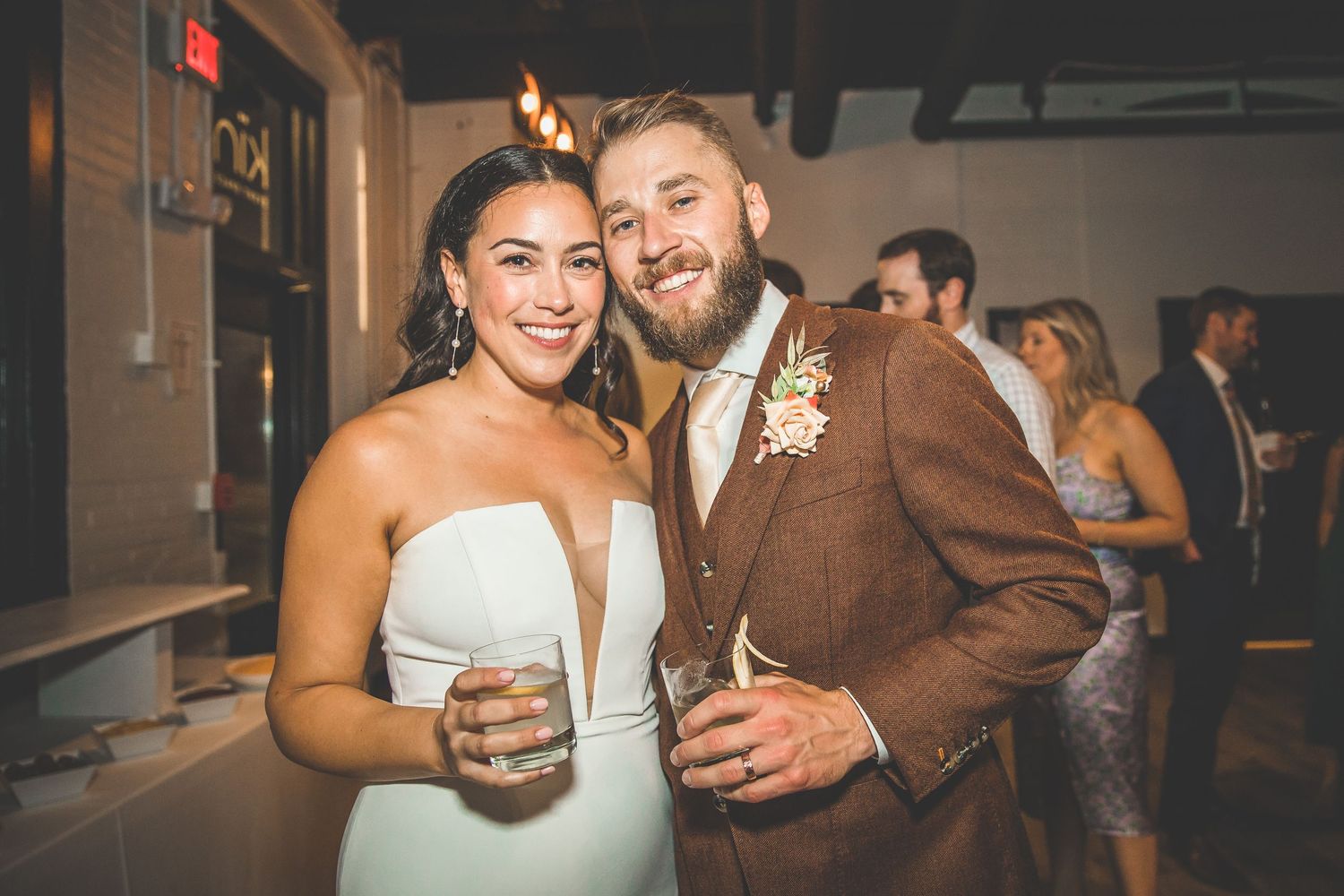 A happy couple celebrates at their wedding reception while holding drinks.