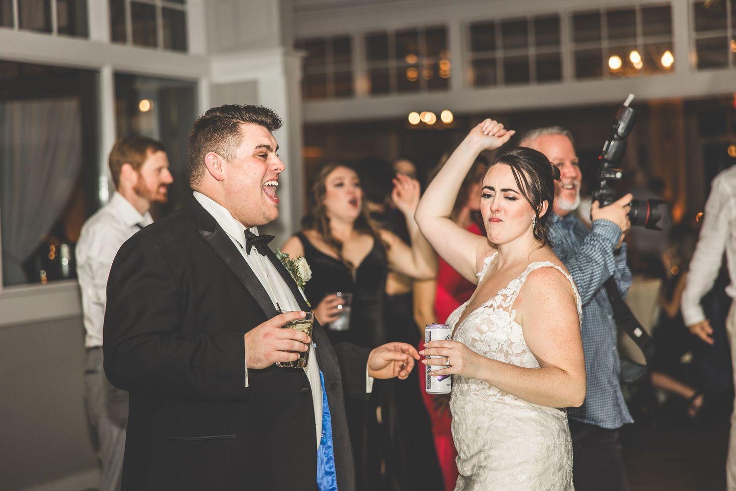 Wedding celebration in full swing with guests dancing at an indoor venue.