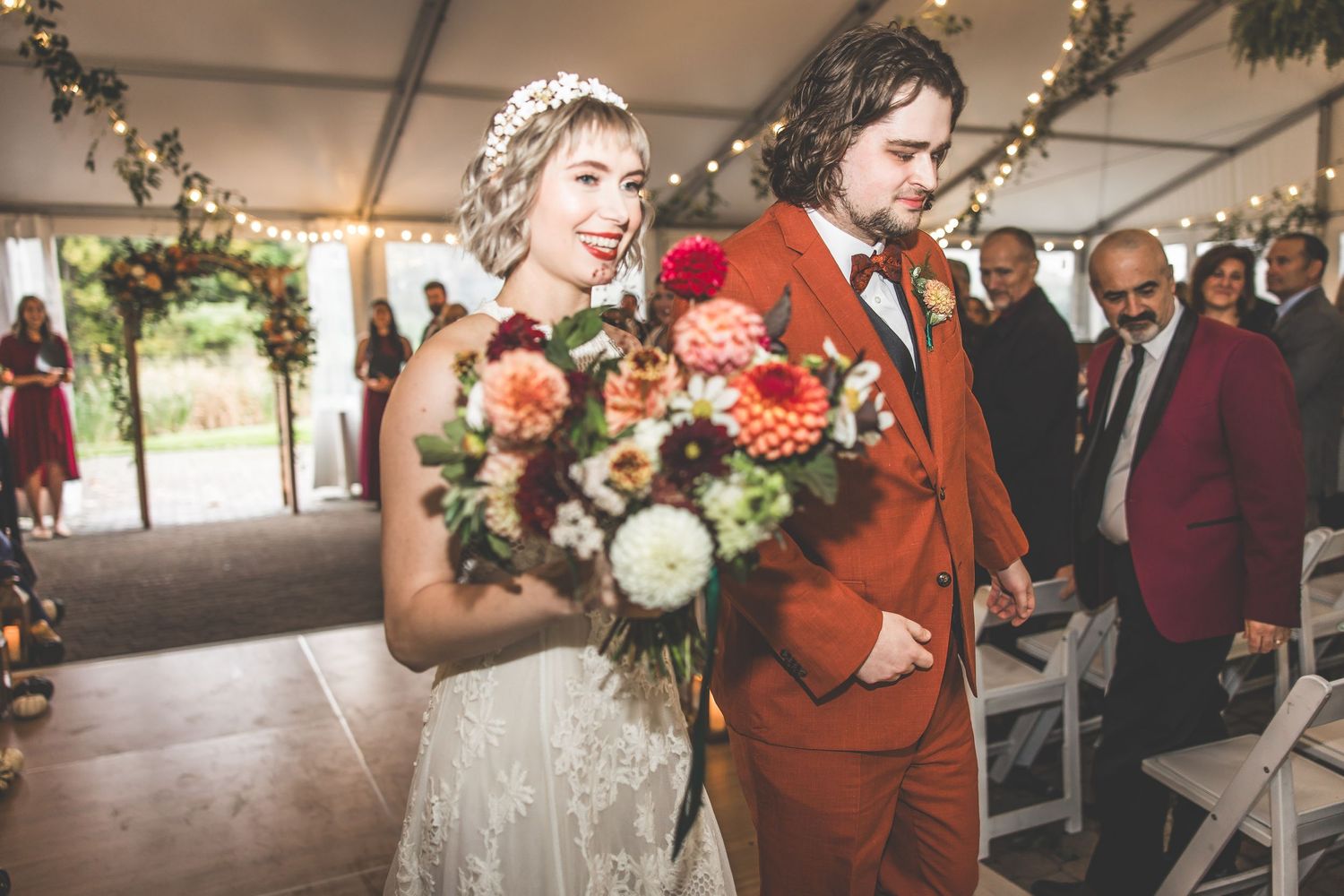 Wedding celebration with autumn-themed floral arrangements and elegant tent setting.