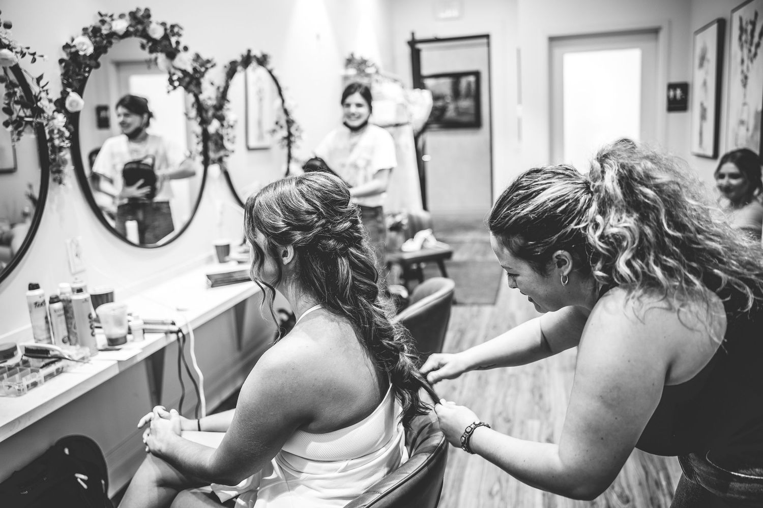 Black and white image of wedding preparation in dressing room with mirrors.