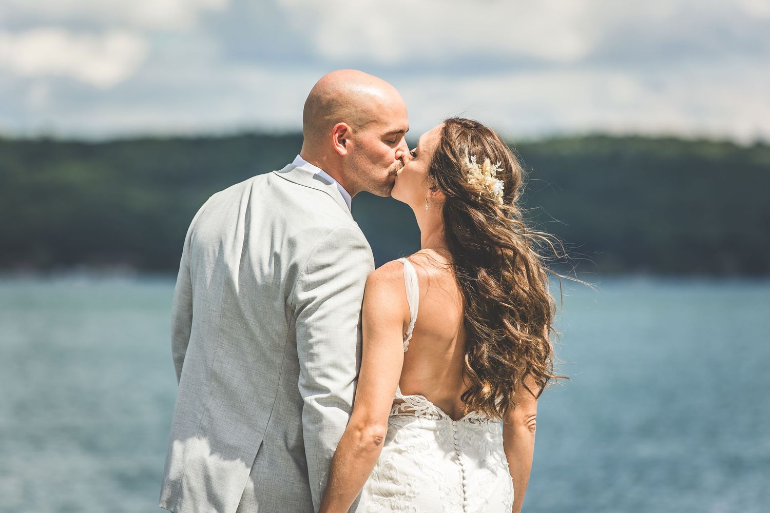 A couple shares an intimate moment against a backdrop of blue water and sky.