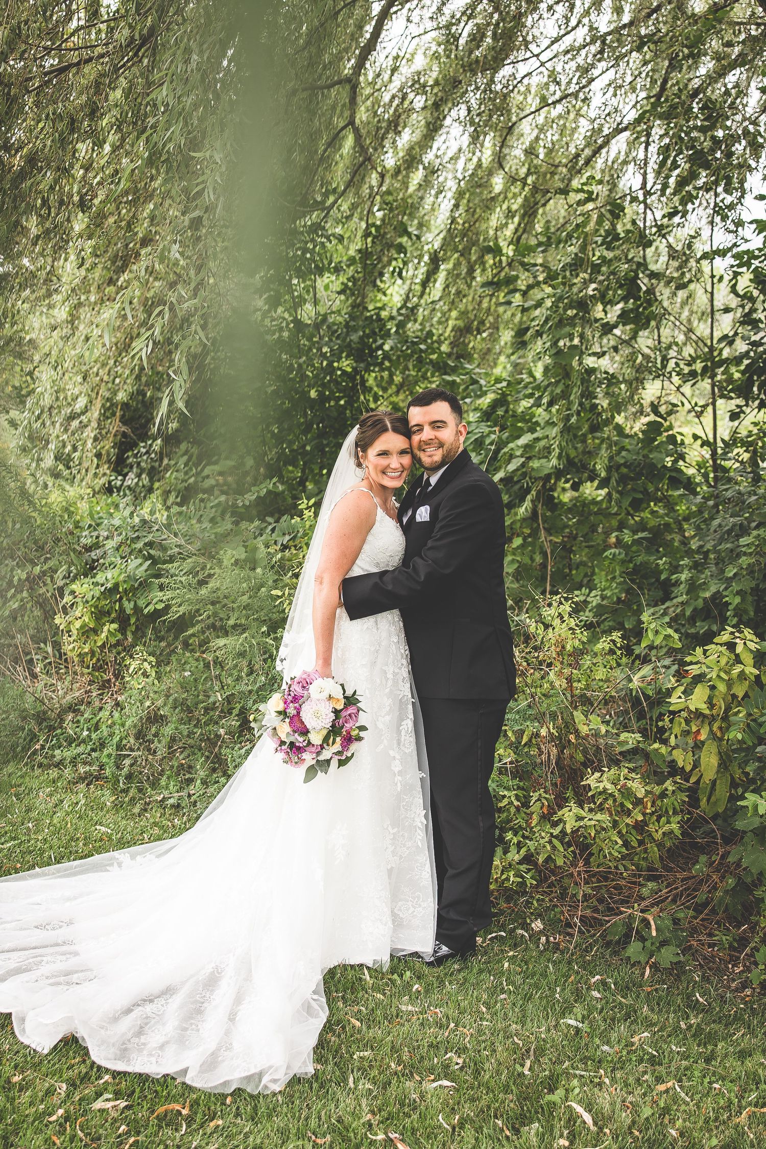 Newlyweds share an intimate moment on their wedding day surrounded by greenery and natural light.