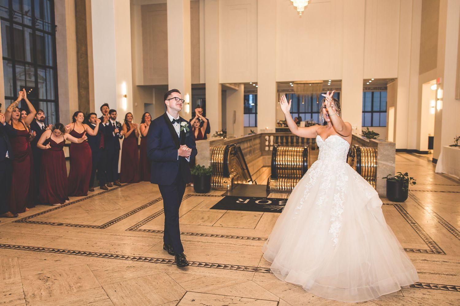 Wedding couple performs romantic dance moves in an ornate ballroom with guests watching.