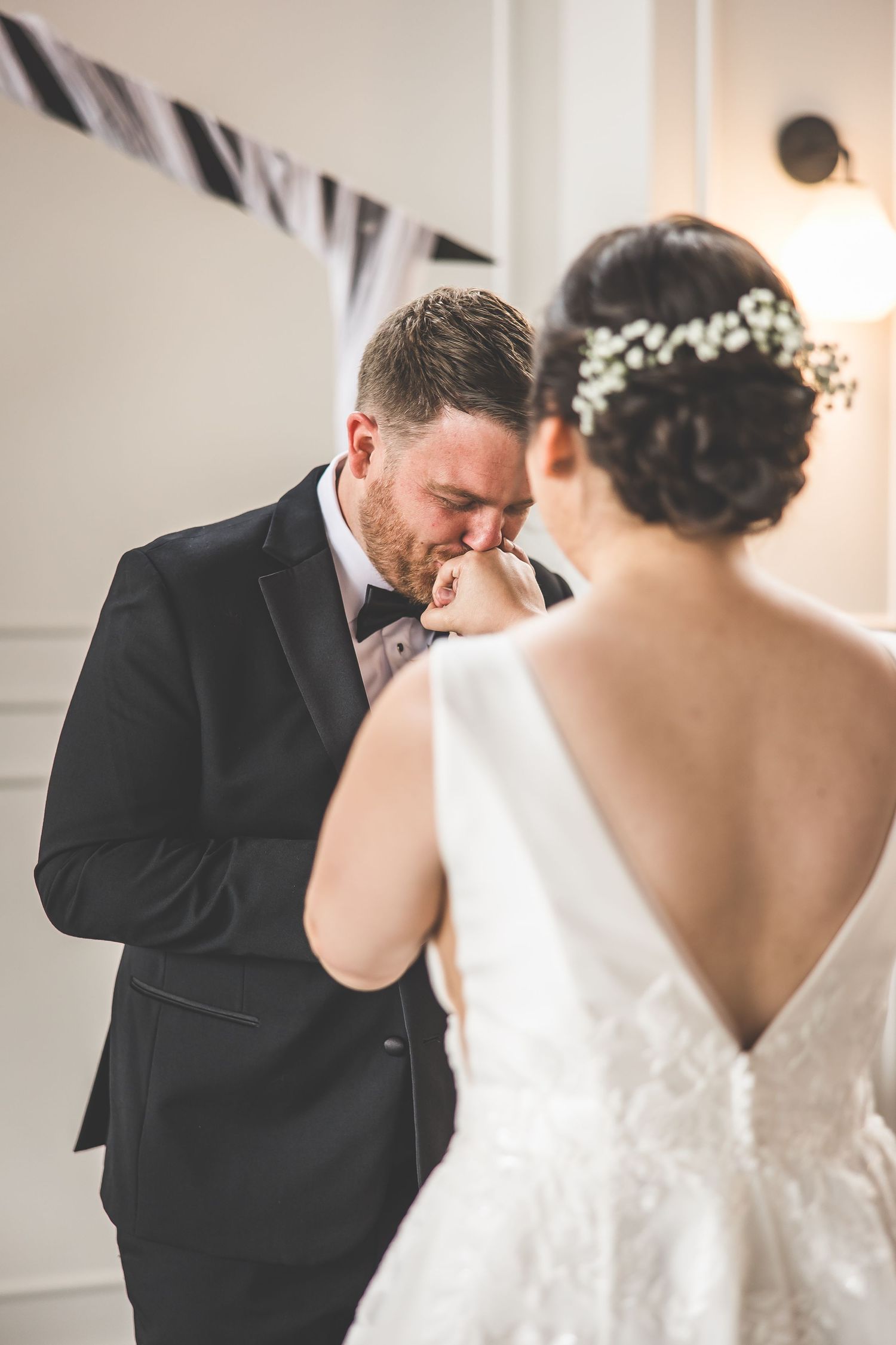 Intimate first look moment between newlyweds in a classic white indoor setting.