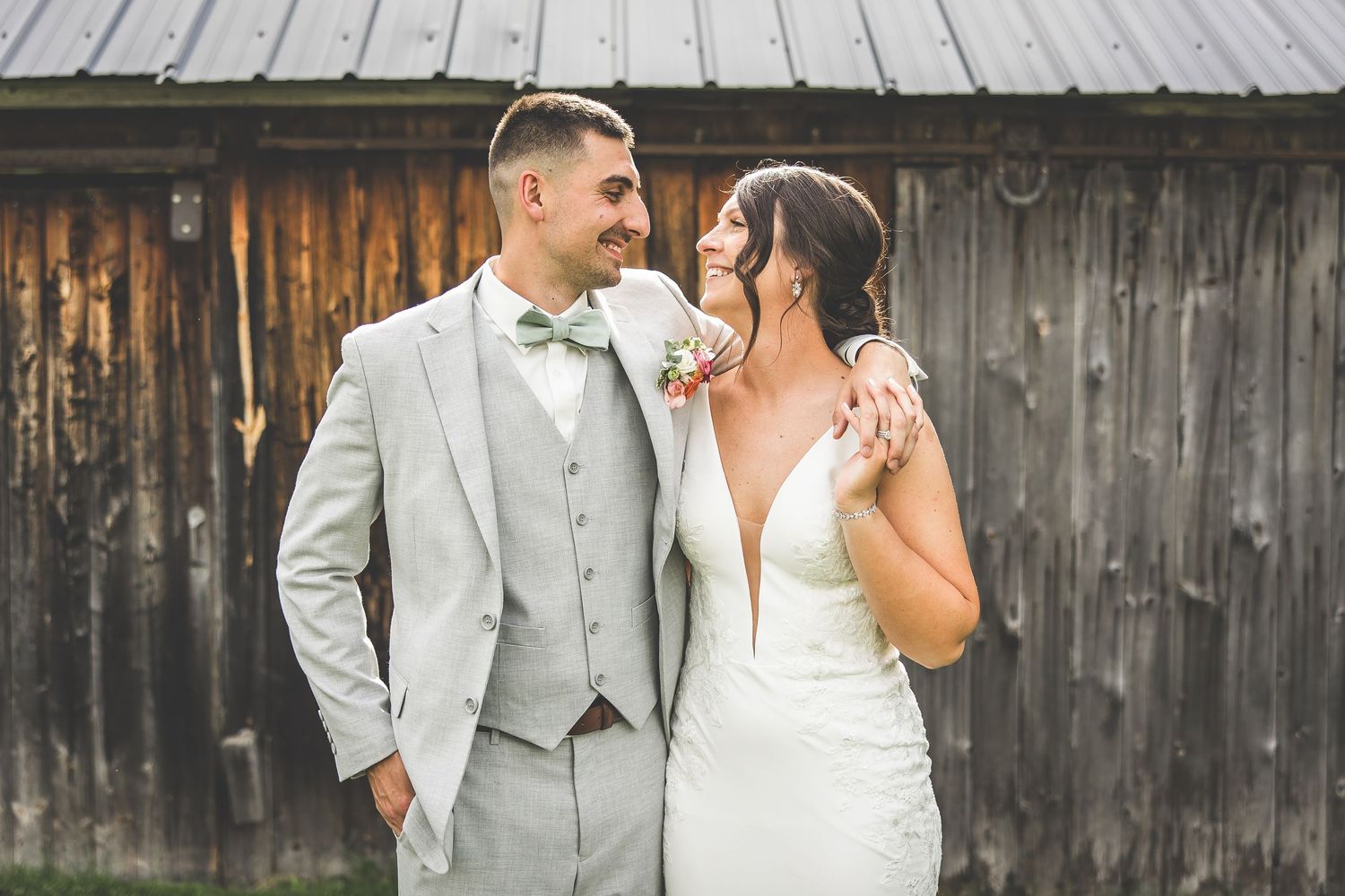Romantic wedding couple portraits against rustic wooden barn backdrop.