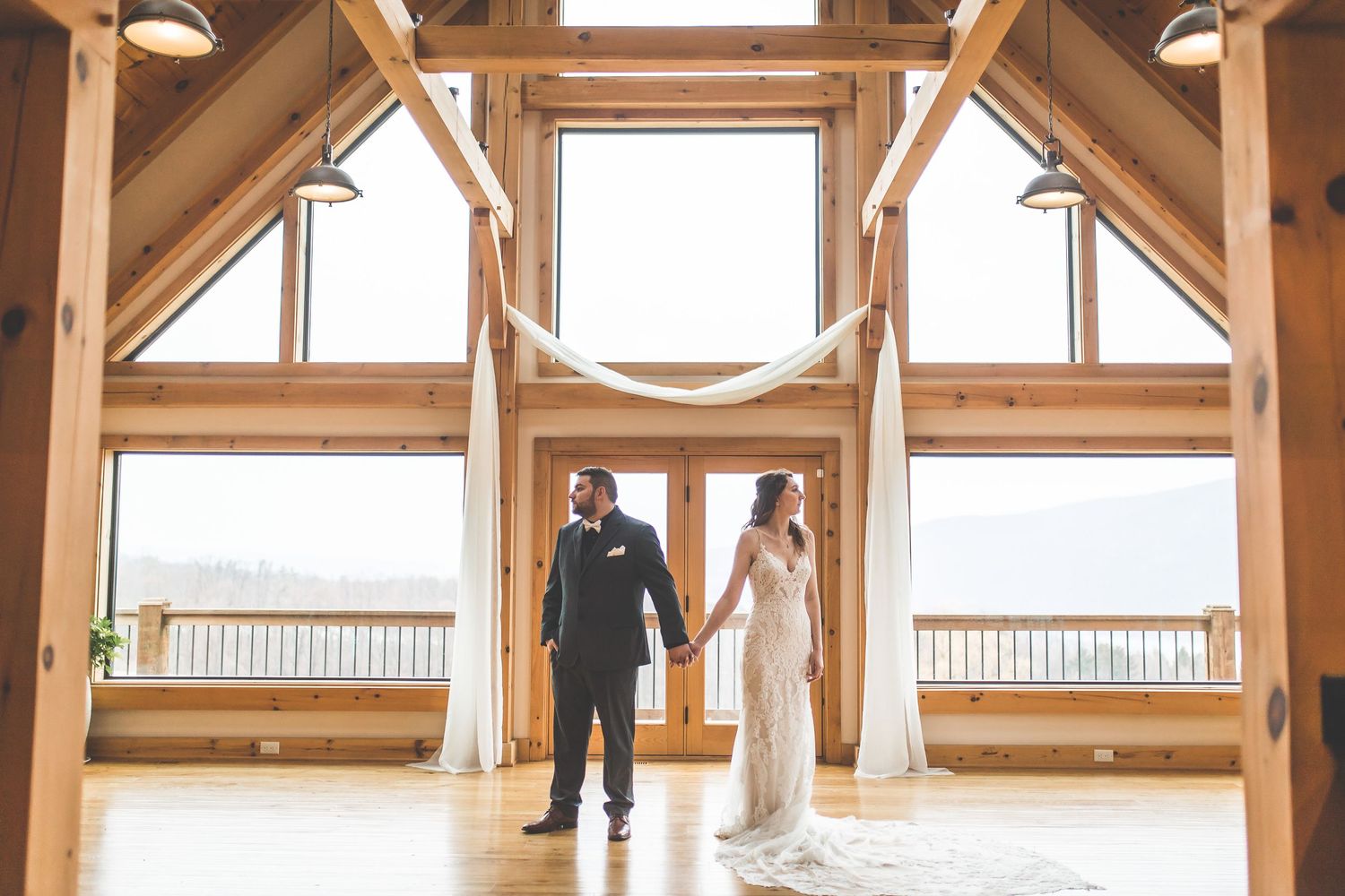 Elegant wedding venue interior with exposed wooden beams and natural lighting streaming through skylights.