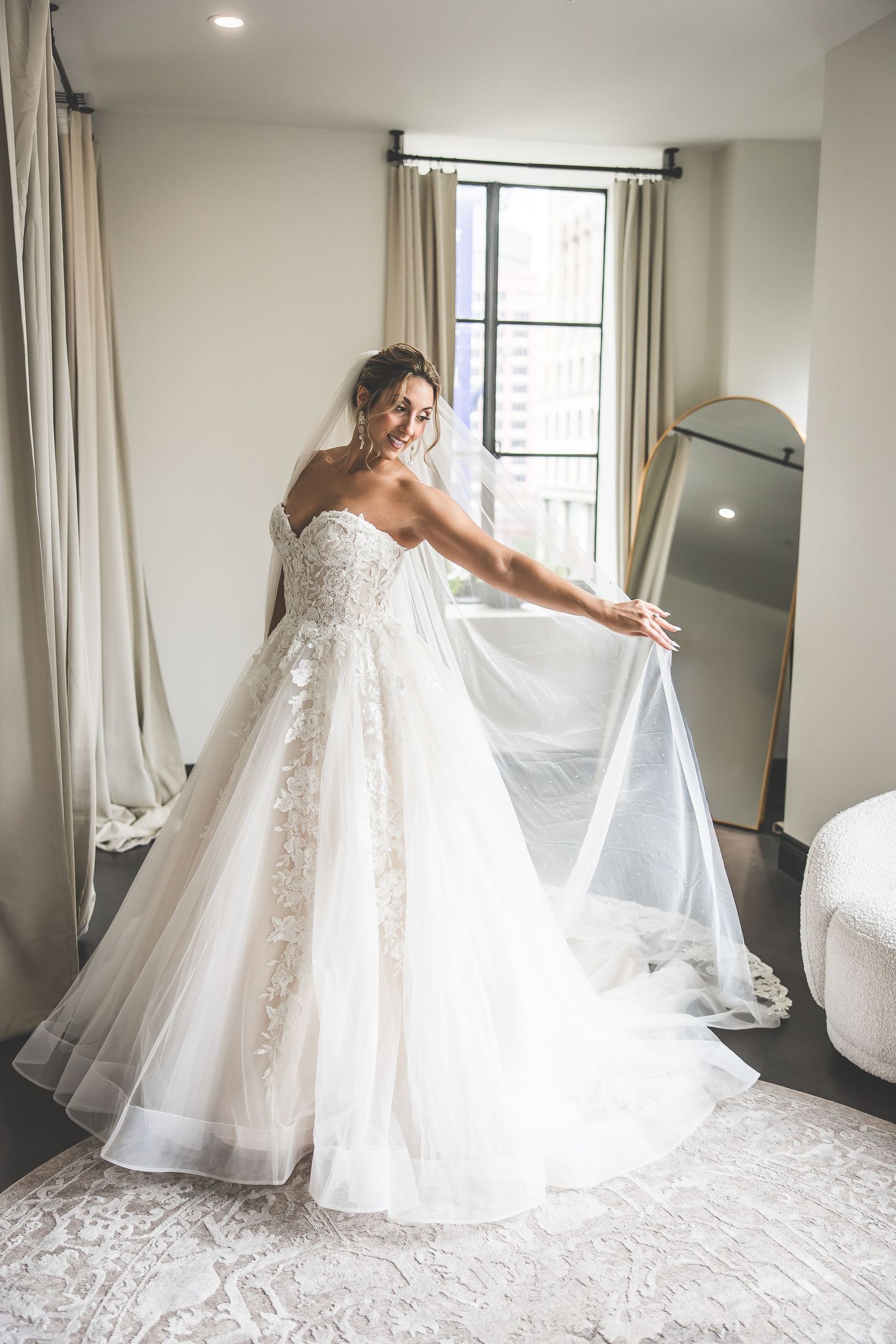 Bride twirling in elegant lace wedding gown in bright modern room.