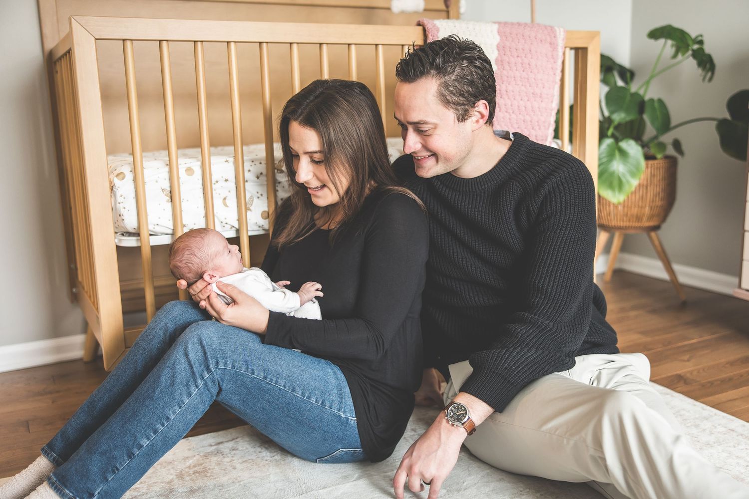 Family relaxing together on wooden floor during intimate home photoshoot.