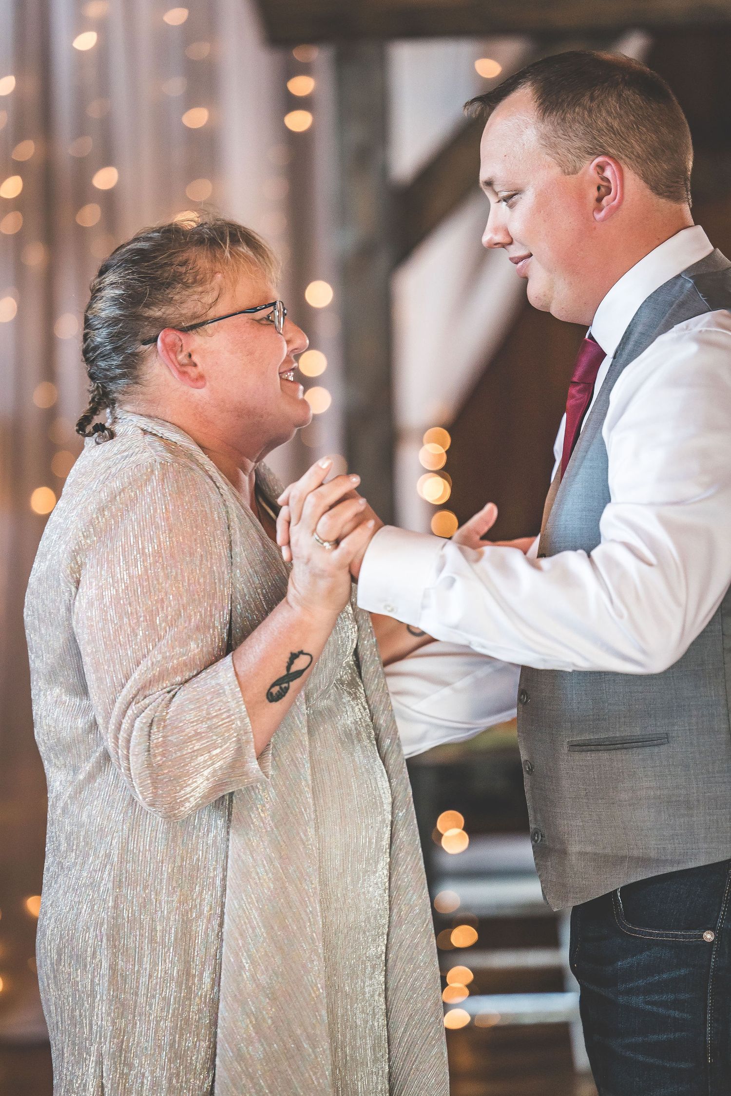 Couples sharing a dance moment in a barn venue with twinkling lights and rustic decor.