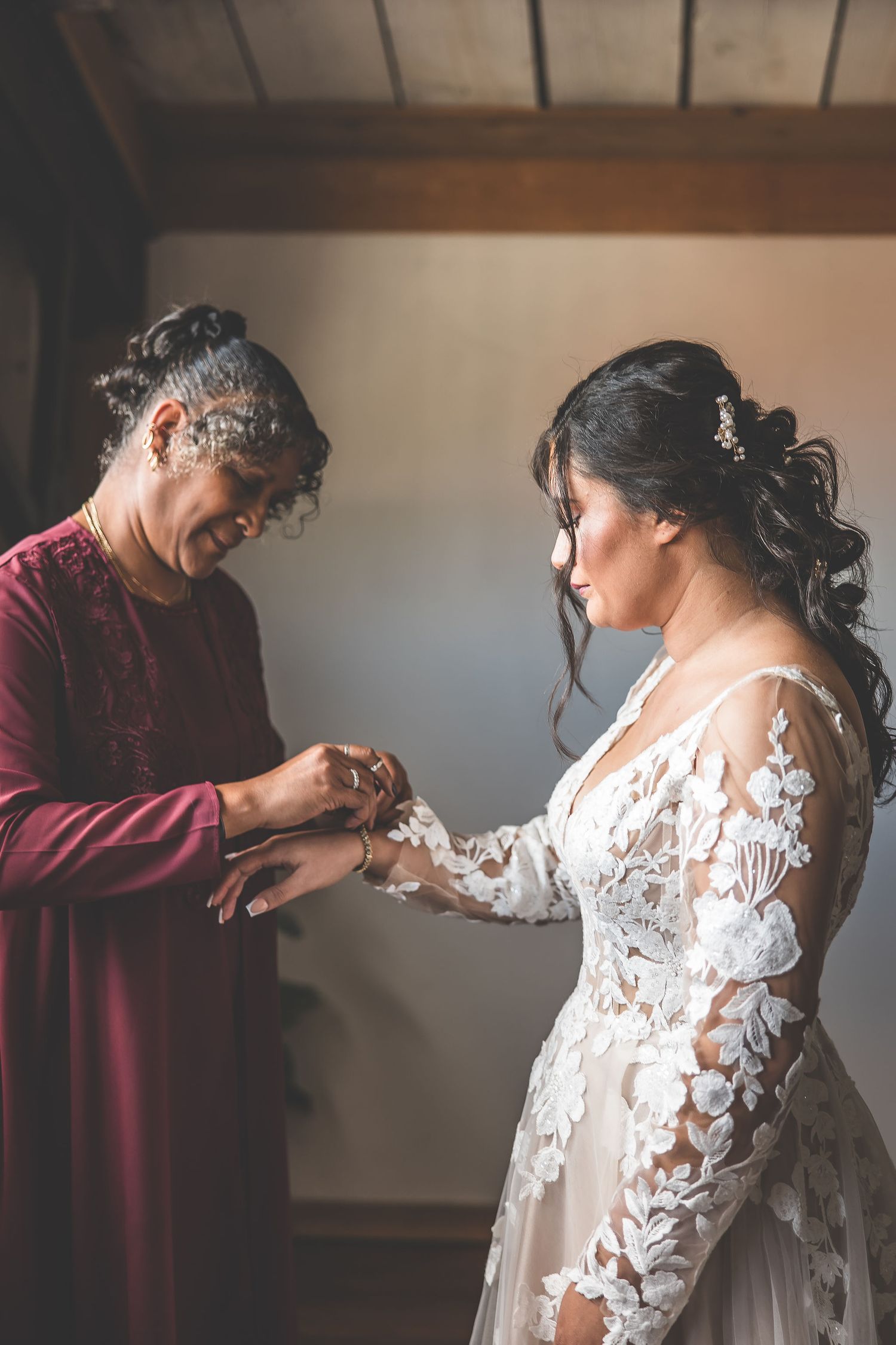 Intimate moment during final wedding preparations in rustic venue with wooden details.