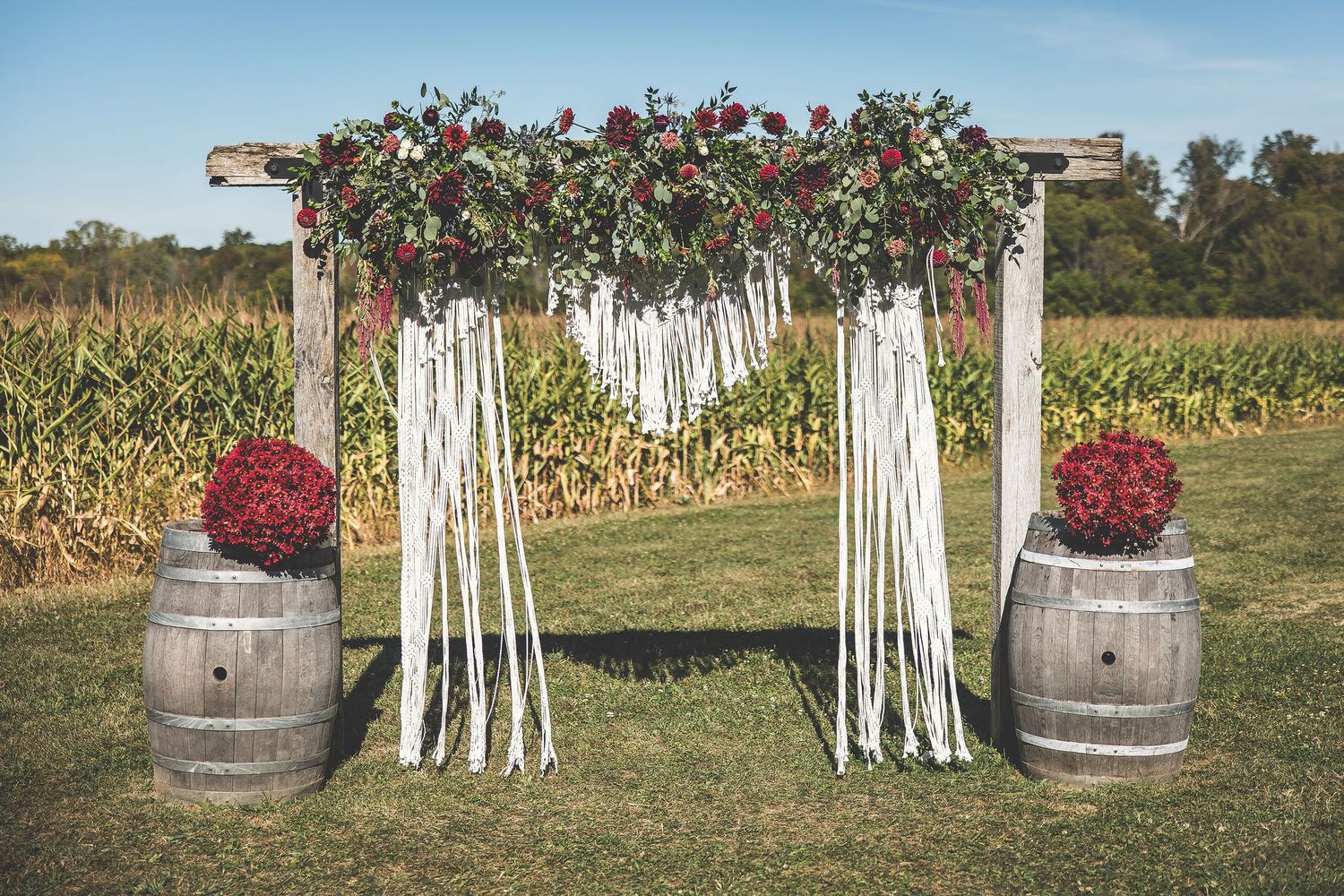 Rustic outdoor wedding decor featuring wooden barrels and white fence panels.