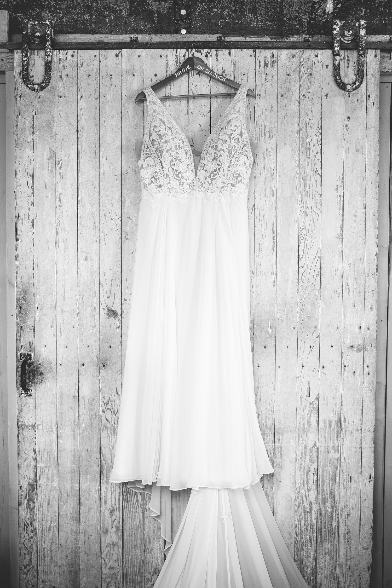 Wedding dress and bridal attire hanging against rustic white wooden wall panels.