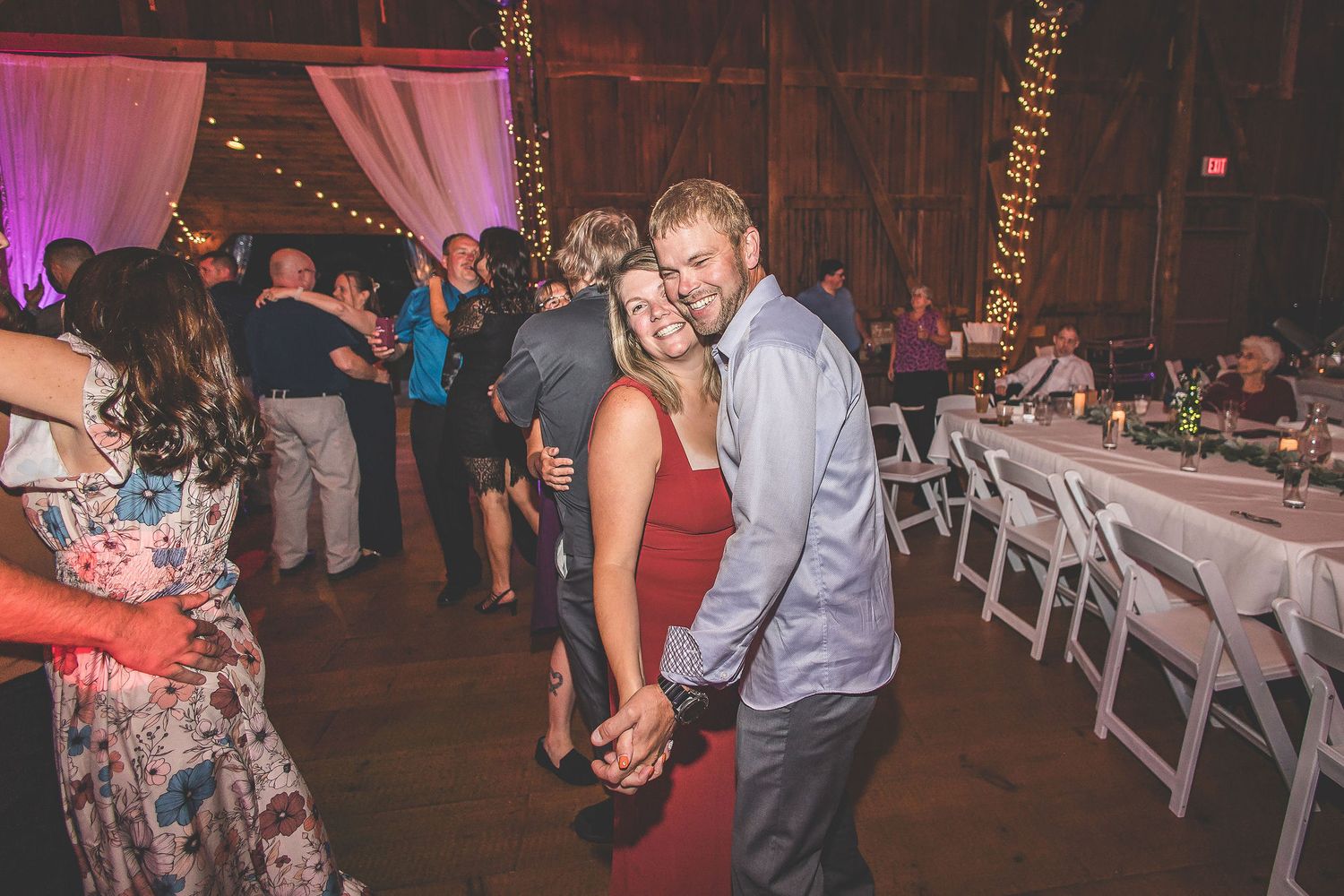 Wedding reception venue with elegant draping, chandeliers and guests dancing.