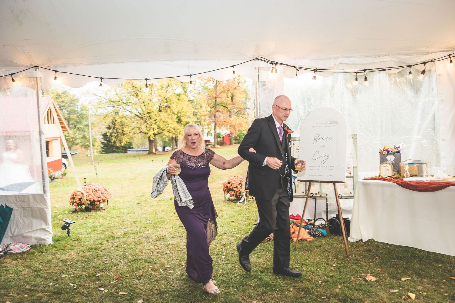 Outdoor wedding venue with white tent and string lights set up for evening celebration.