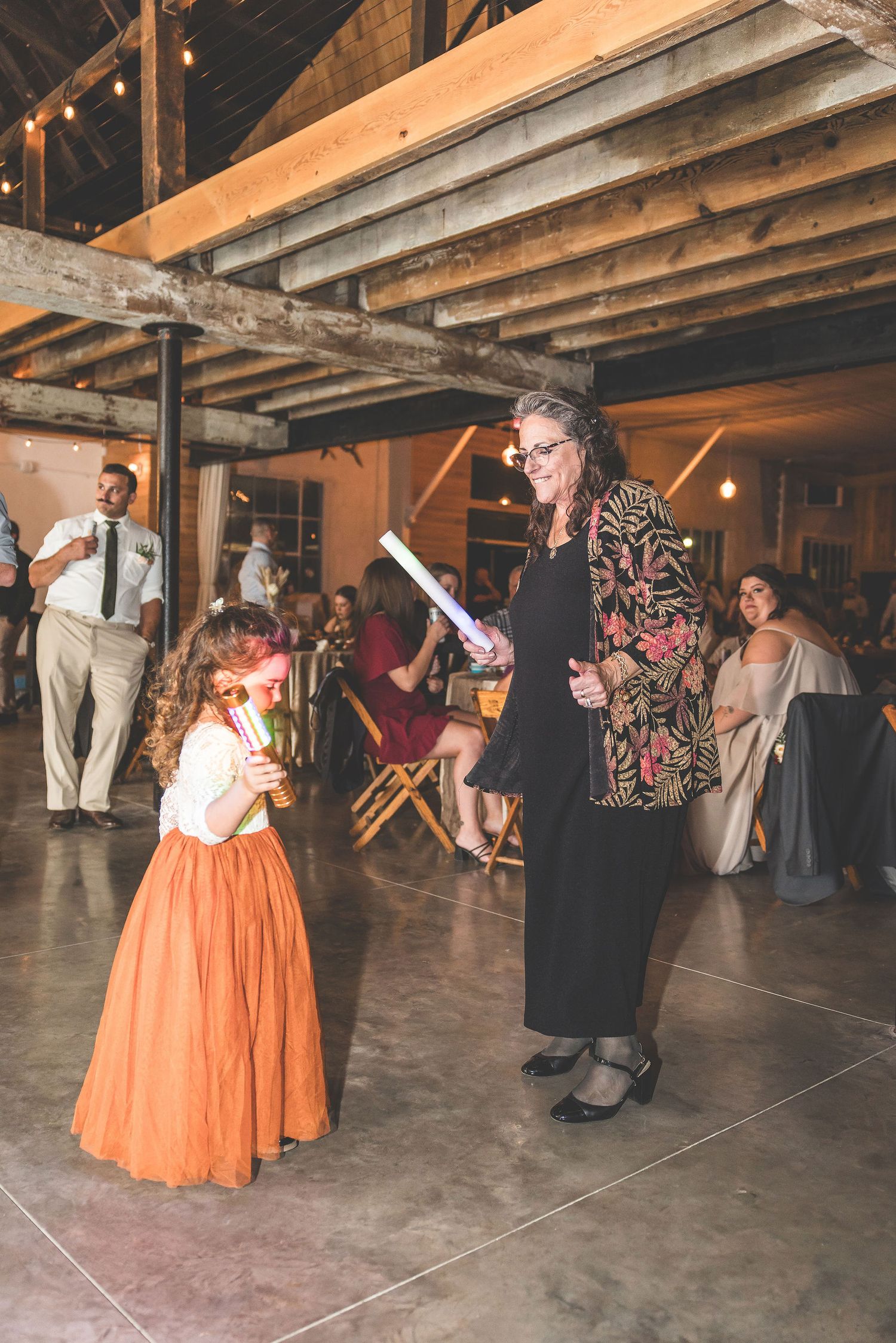Wedding celebration in an industrial venue with exposed beams and string lights.