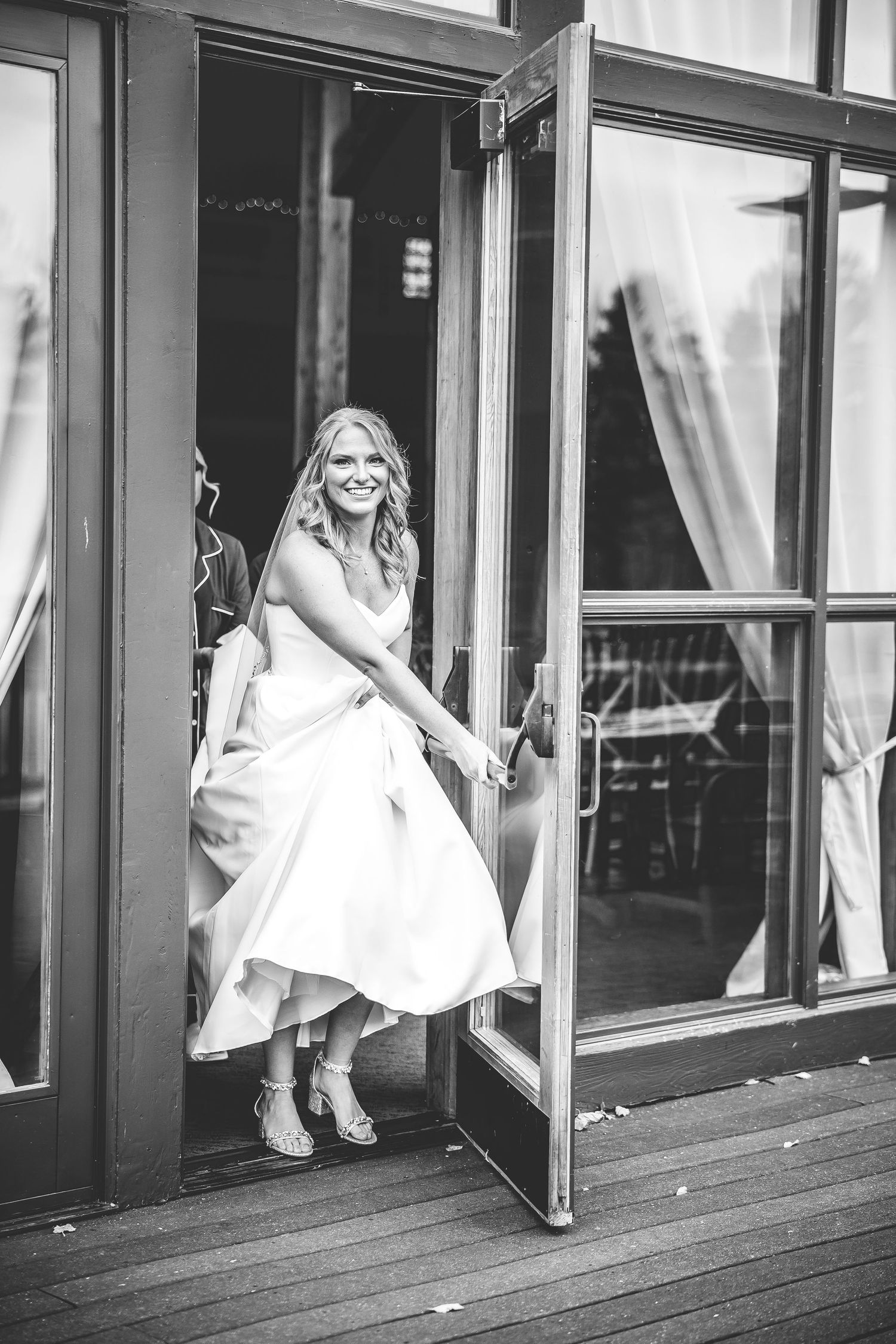 Black and white photo of wedding dress details on a wooden deck.