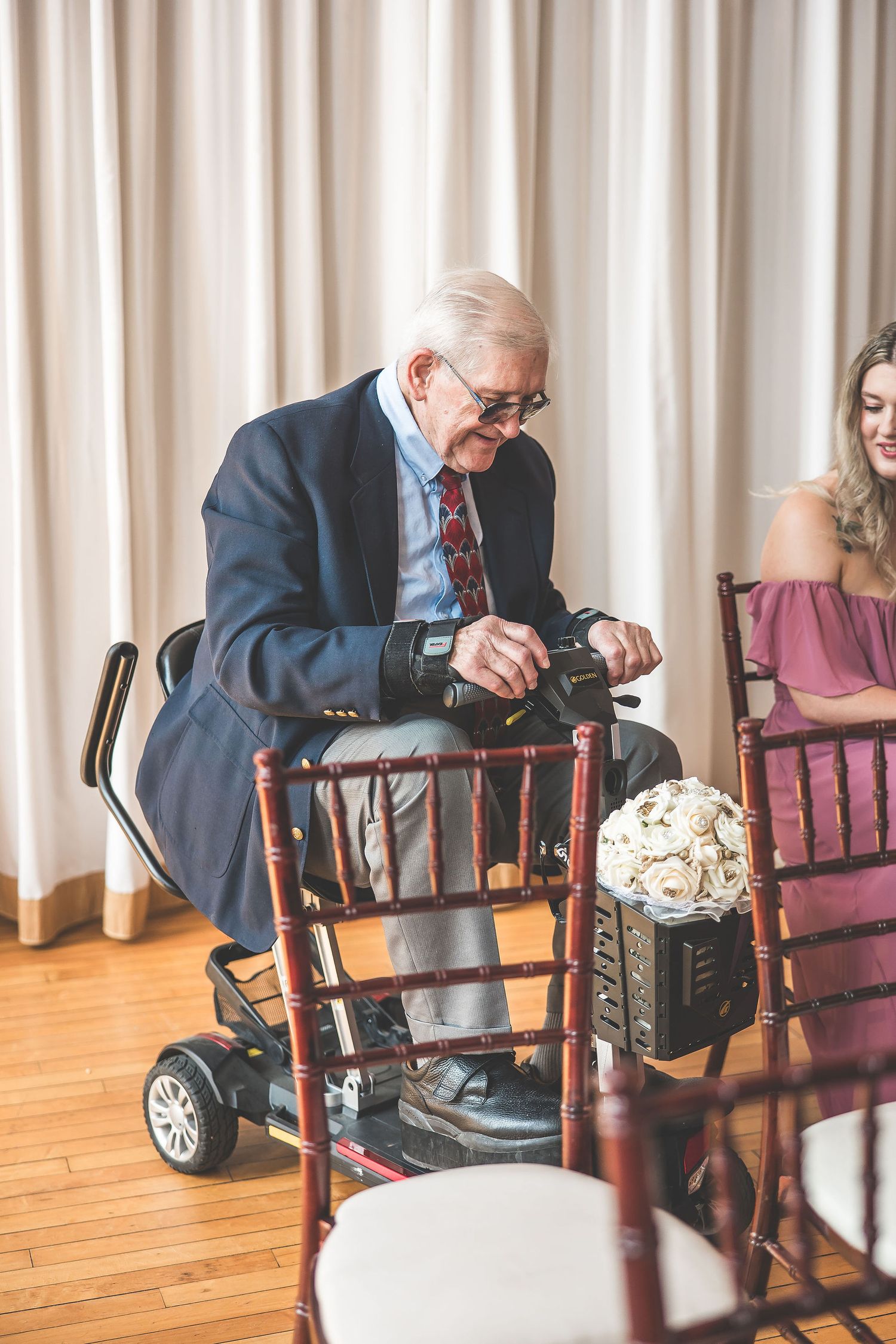 Guest seated in wooden chairs during an indoor wedding ceremony.