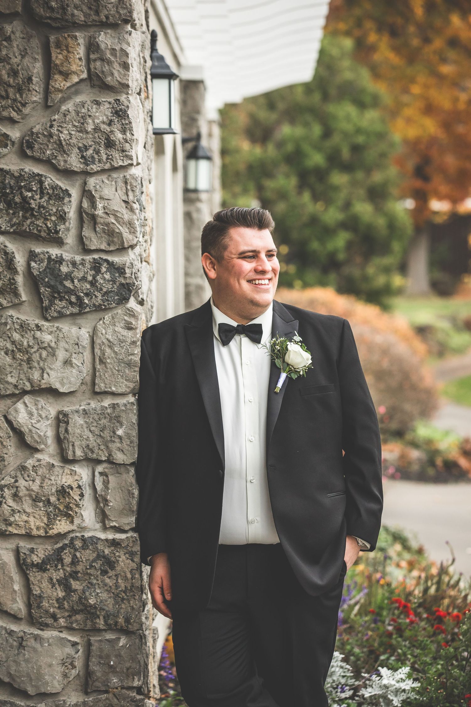 Formal portraits against stone wall with autumn foliage in elegant wedding setting.