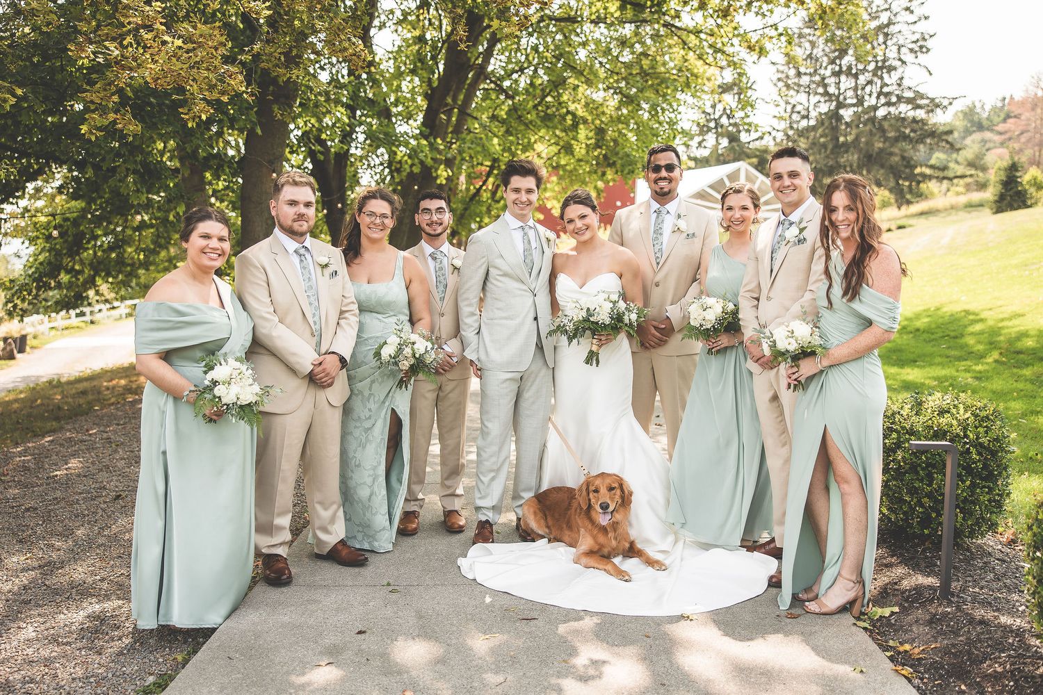 Wedding party poses together outdoors with mint green dresses and light colored suits.