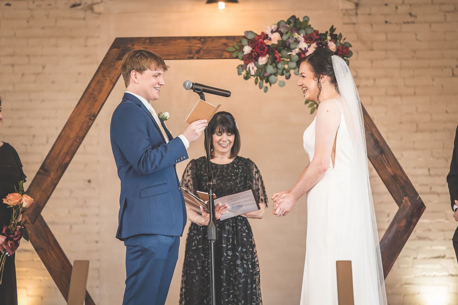 Wedding ceremony with rustic wooden backdrop and elegant floral arrangements.