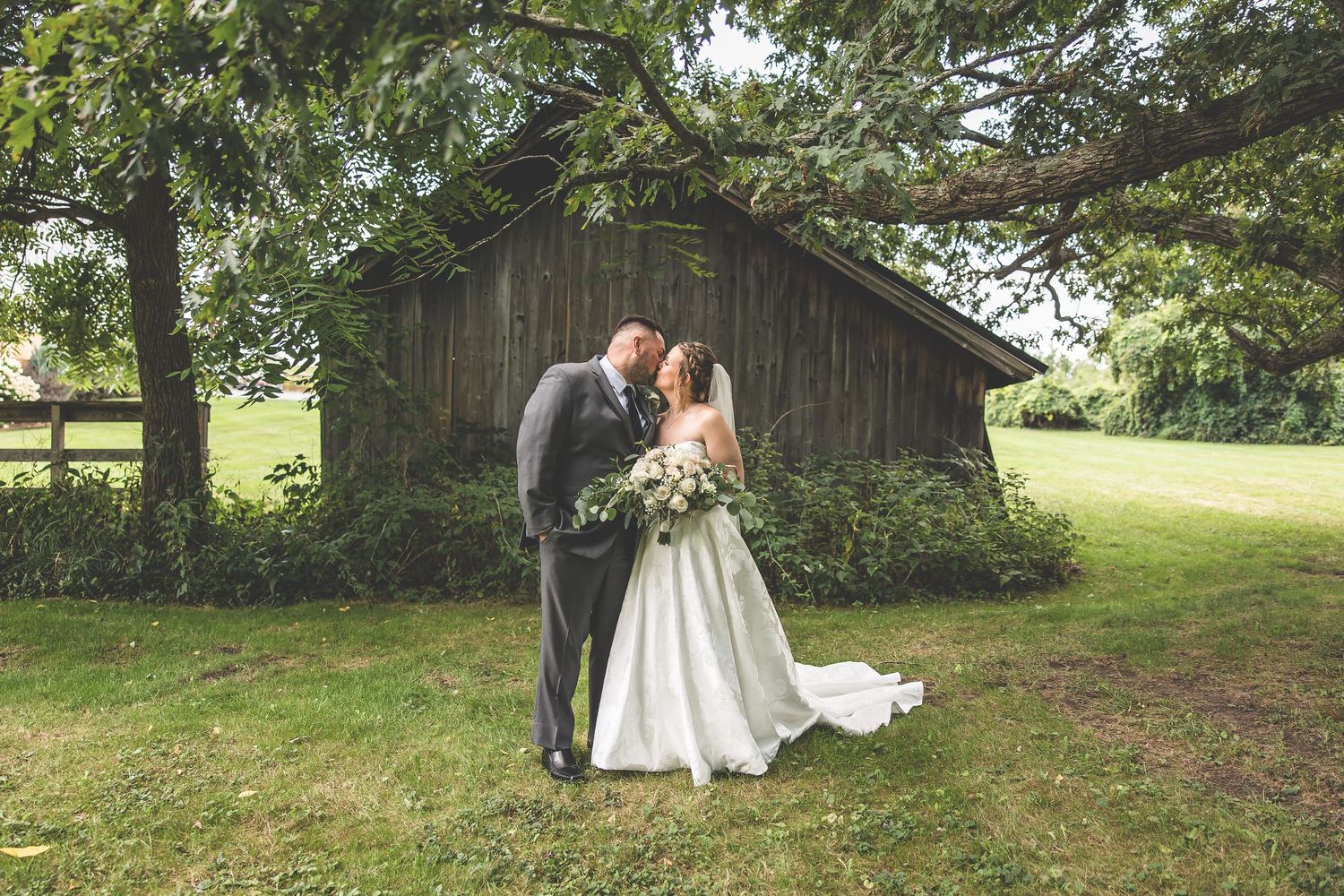 Rustic outdoor wedding venue with barn and green landscape.