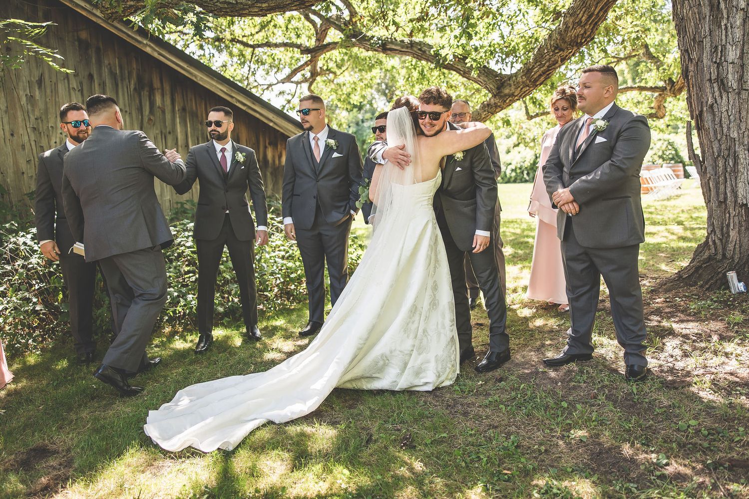 Wedding party celebrates with joyful poses outside a rustic barn venue.