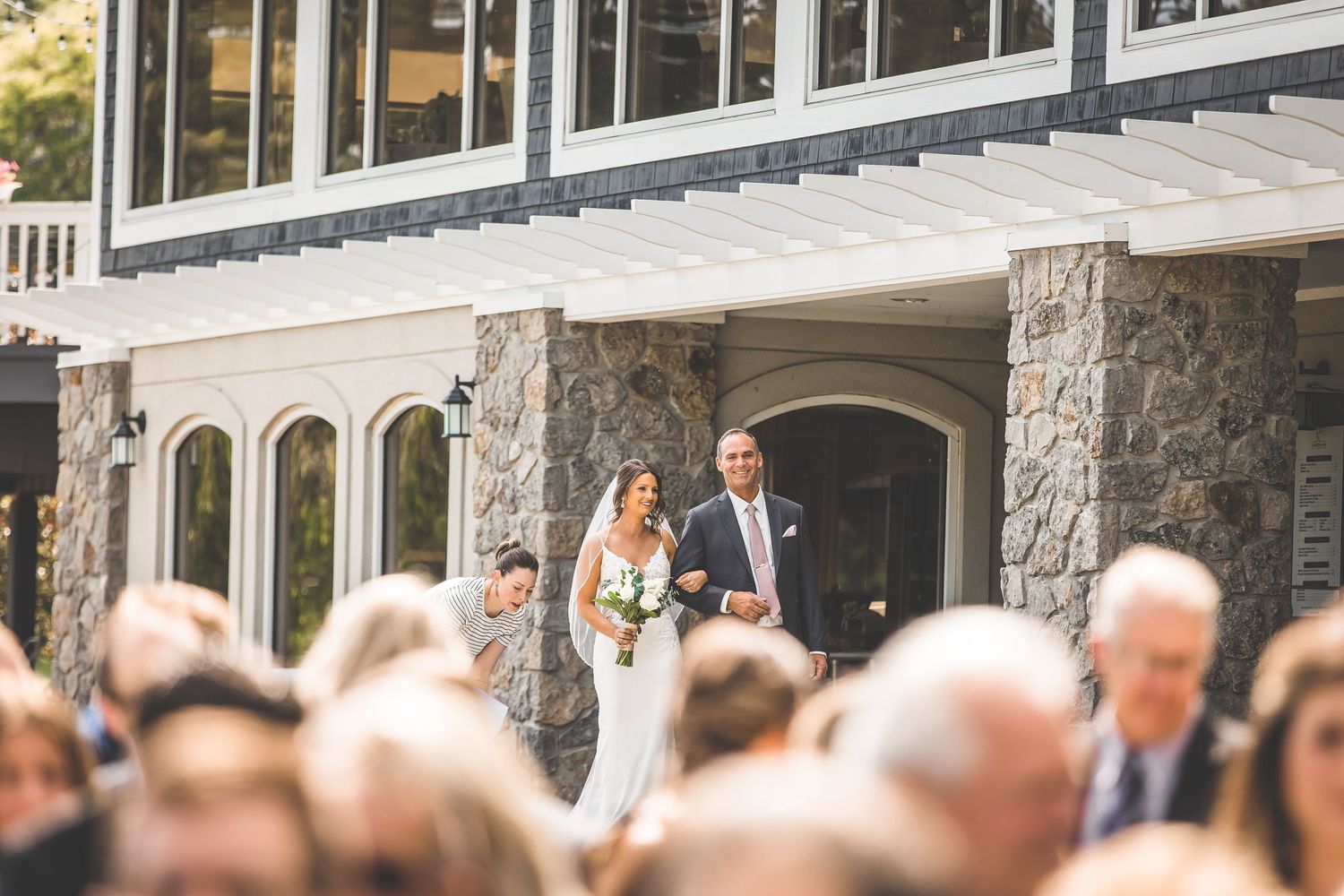 Stone building exterior with wedding guests gathering under covered walkway.